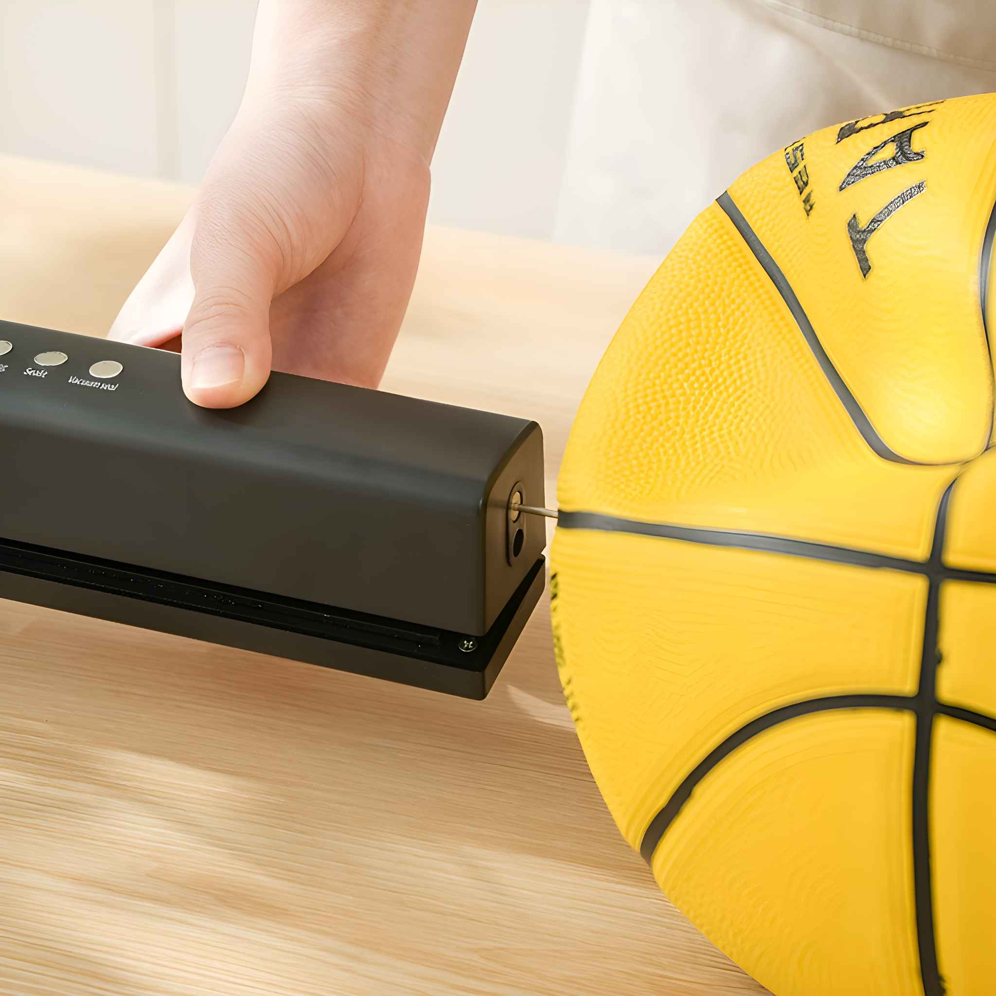 Eine Hand verwendet ein Vakuumiergerät auf einem Basketball. Der Ball ist gelb mit schwarzen Linien. Das Siegelgerät ist schwarz.