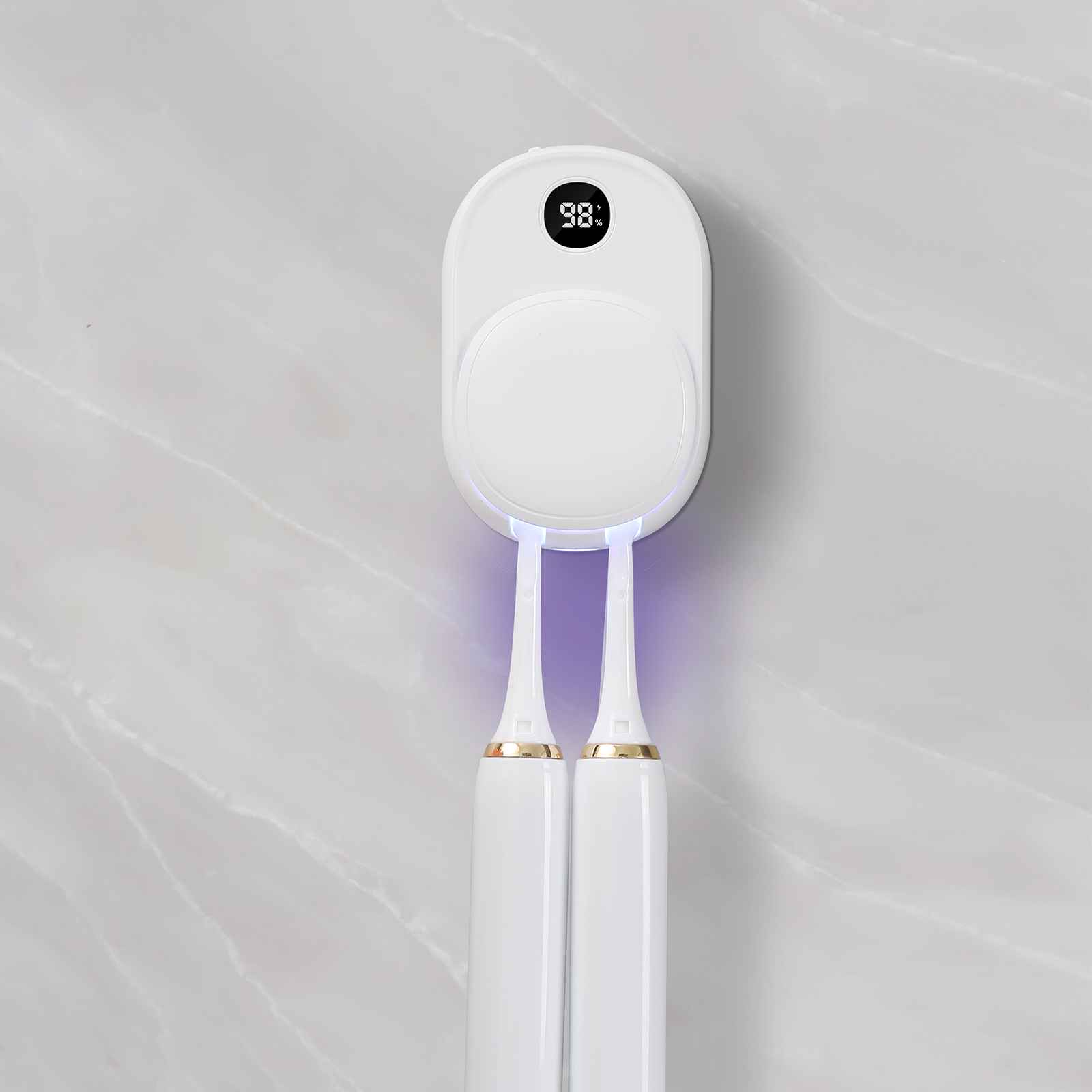 Ein weißer Zahnbürstenhalter mit zwei elektrischen Zahnbürsten. Der Halter hat ein Display mit 98%. Die Wand ist marmorartig.