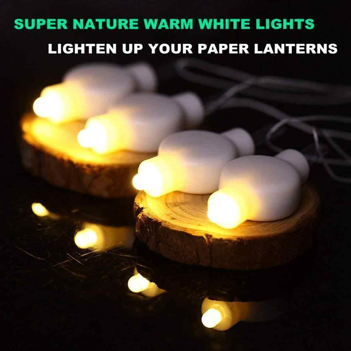 Weiße Lichter auf Holzscheiben leuchten. Text: 'SUPER NATURE WARM WHITE LIGHTS LIGHTEN UP YOUR PAPER LANTERNS'.