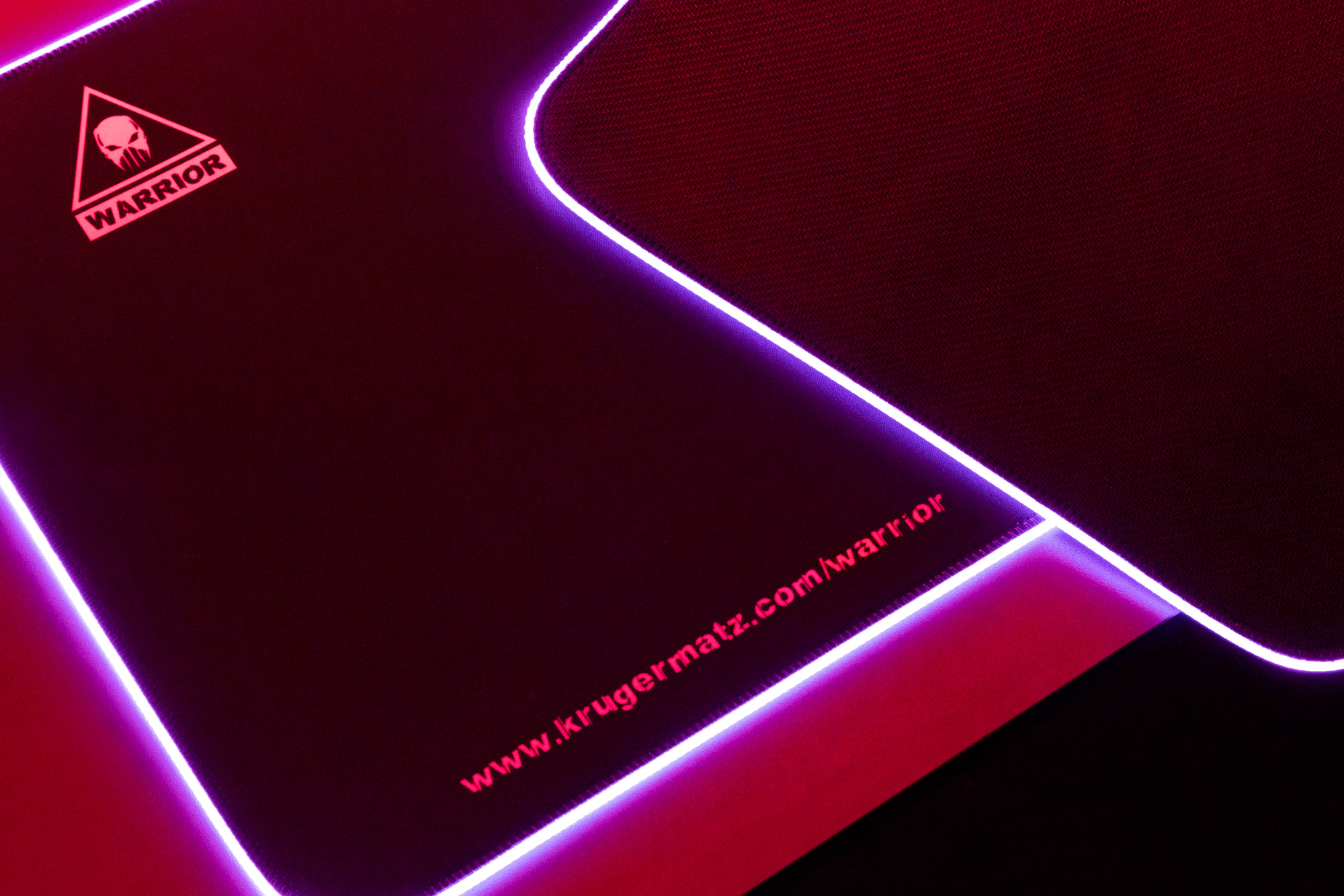 Podkładka pod mysz dla graczy z logo czaszki i napisem "WARRIOR". Krawędzie są podświetlane neonem. Widoczny adres strony internetowej.