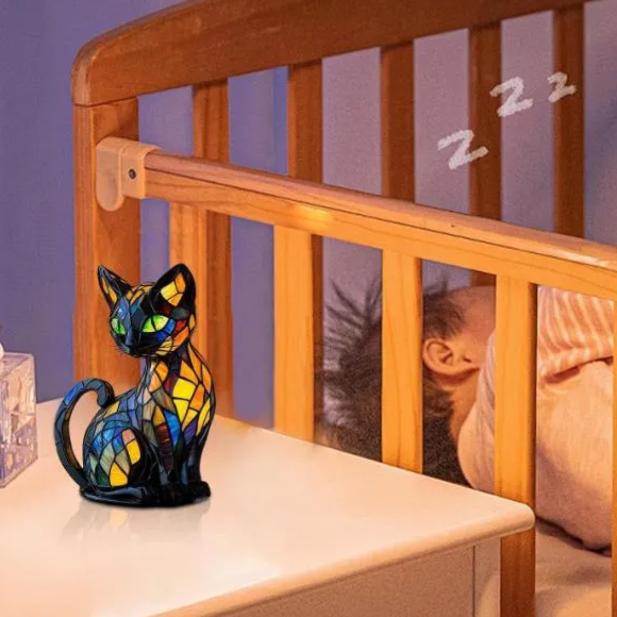 Eine Glasmalerei-Katzenstatue steht auf einem Nachttisch neben einem Kinderbett. Ein Baby schläft im Kinderbett. Zz's sind über dem Kinderbett.