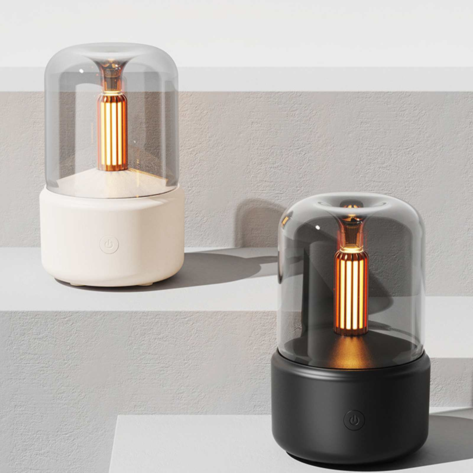 Zwei moderne Lampen, eine weiße, eine schwarze, auf einer geschichteten Oberfläche. Jede hat eine Glasabdeckung und ein orangefarbenes Licht.