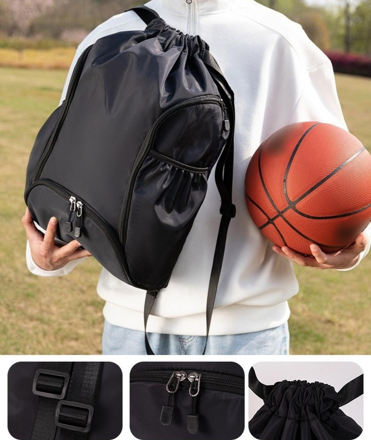 Eine Person hält einen schwarzen Rucksack mit Kordelzug und einen Basketball. Die Person trägt ein weißes Hemd. Der Hintergrund ist grünes Gras.