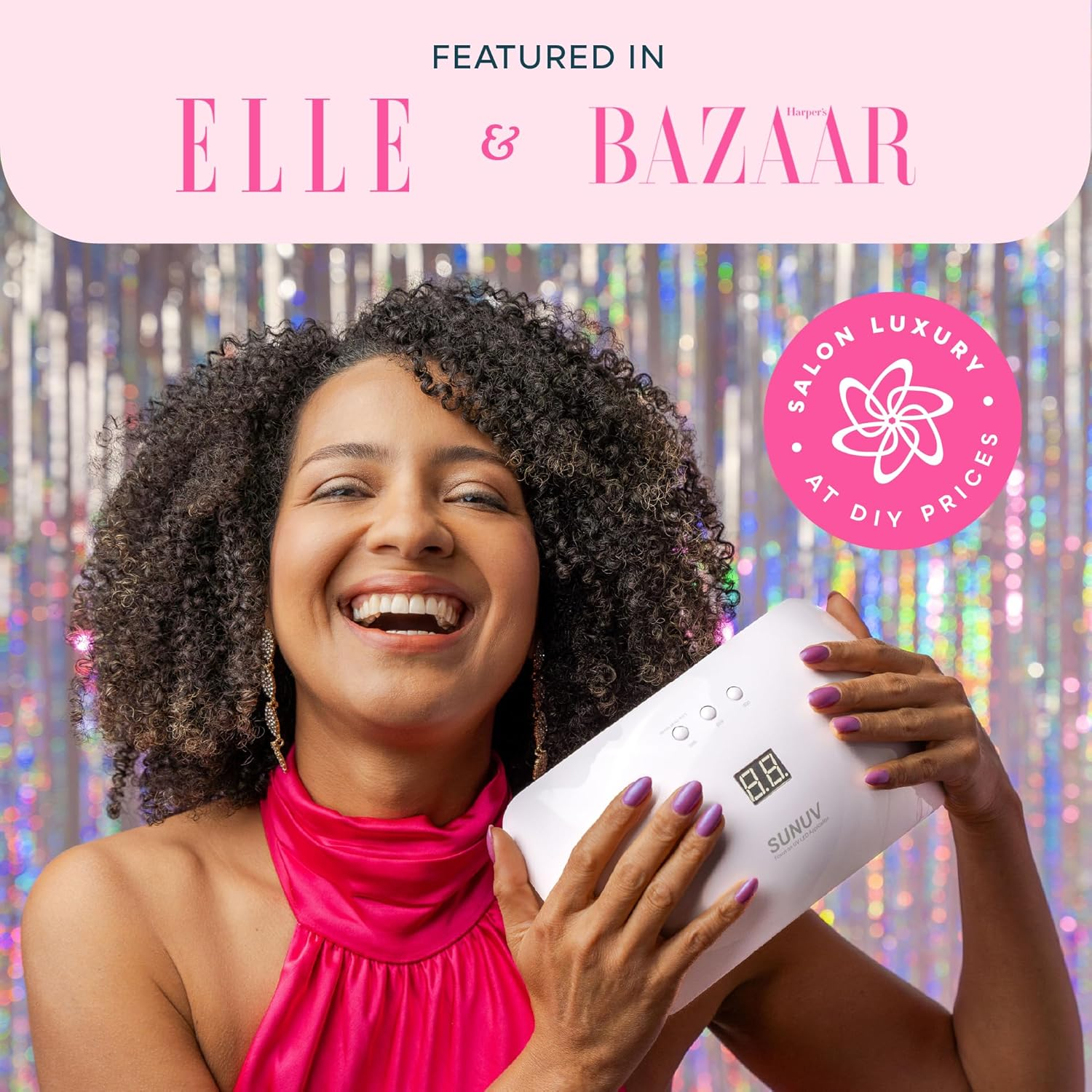 Eine Frau lächelt und hält eine UV-Nagellampe. Sie trägt ein rosa Top. Der Hintergrund zeigt Logos von Elle & Bazaar und einen Aufkleber 'Salon Luxury'.