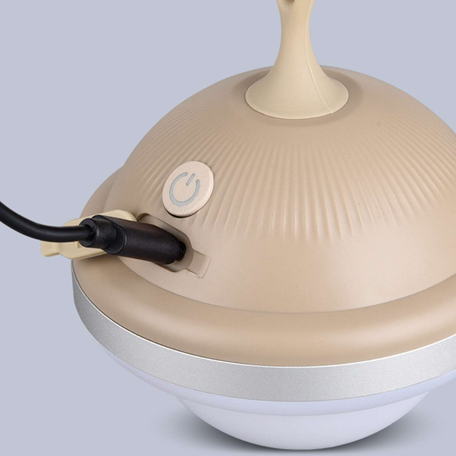 Ein beigefarbener, gewölbter Lampensockel mit Ein-/Aus-Taste. Ein schwarzes Kabel wird seitlich eingesteckt. Die Basis ist weiß.