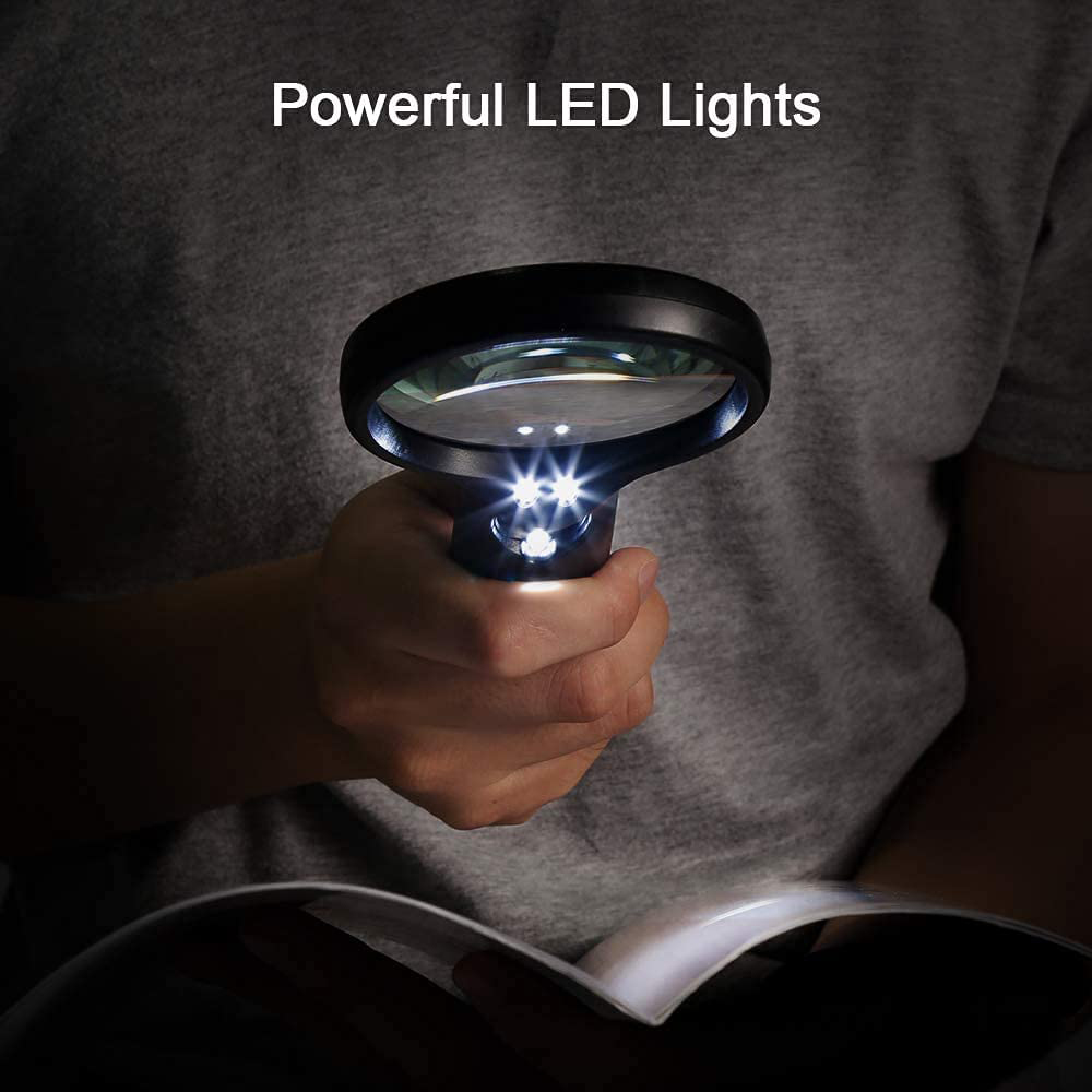 Eine Hand hält eine Lupe mit hellen LED-Leuchten über einem geöffneten Buch. Die Person trägt ein graues Hemd.