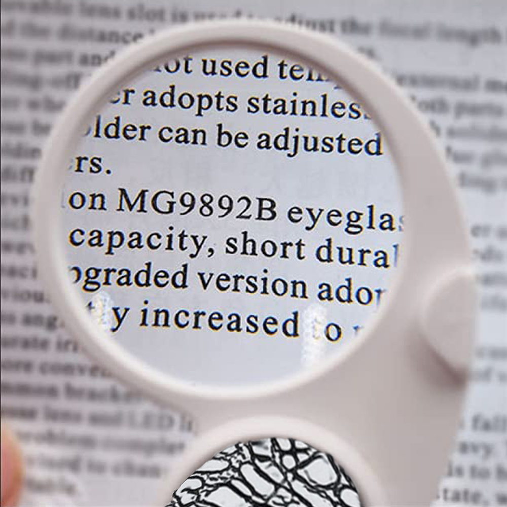 Eine weiße Lupe über Text. Der Text lautet 'MG9892B Eyeglas-Kapazität'. Unten ist ein kleines Schwarz-Weiß-Muster zu sehen.