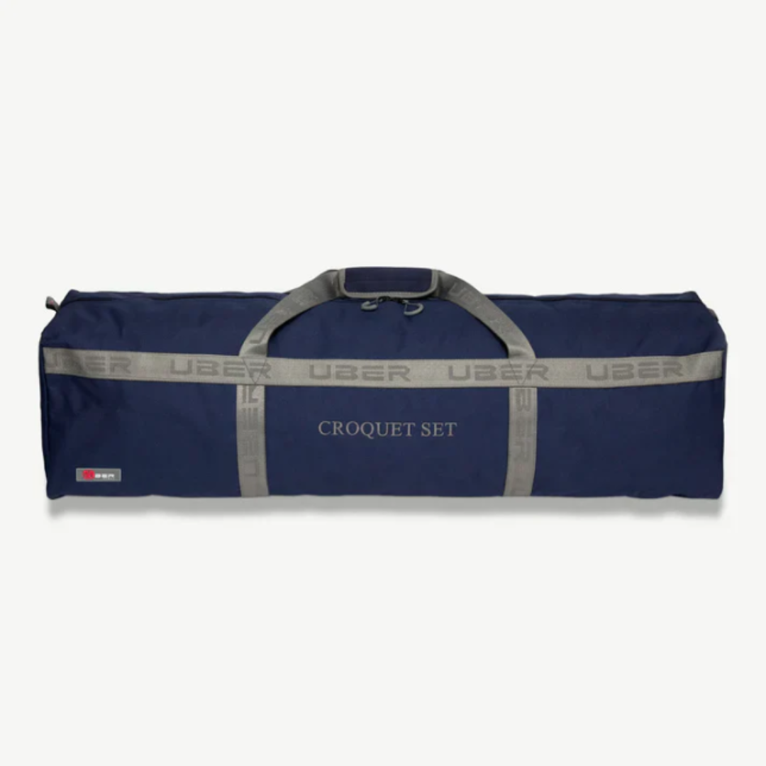 Eine marineblaue Reisetasche mit dem sich wiederholenden Wort "UBER" und dem Aufdruck "CROQUET SET". Graue Griffe und Riemen. Weißer Hintergrund.