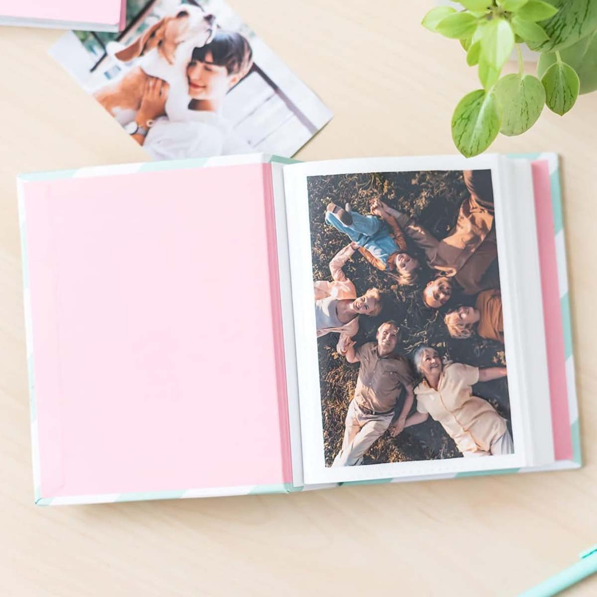 Album photo ouvert sur une table en bois. Une photo montre un groupe de personnes allongées sur l'herbe. Une autre photo montre une personne et un chien.