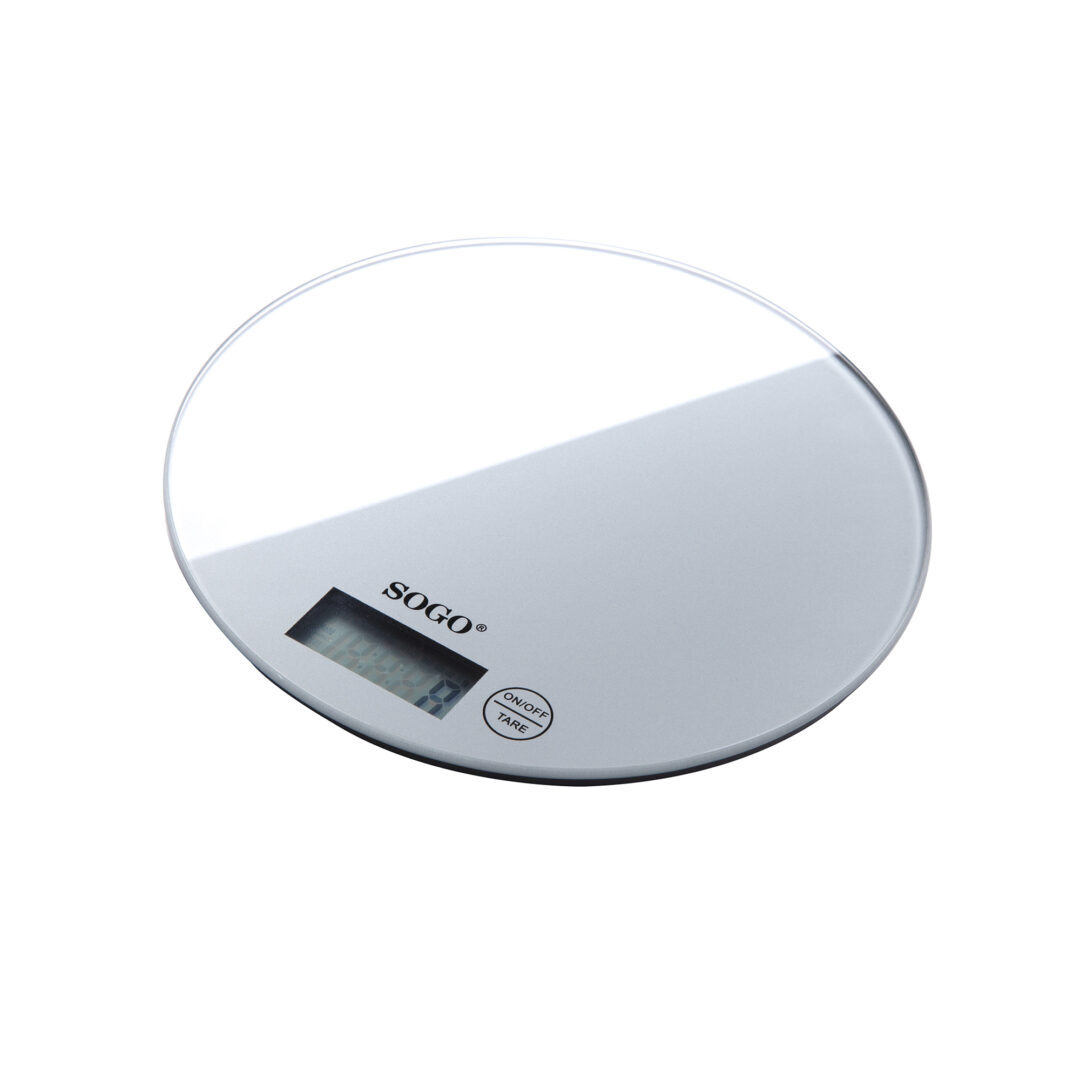 Una báscula de cocina redonda y plateada SOGO con una pantalla LCD que muestra números. Tiene un botón de encendido/apagado y tara. Fondo blanco.