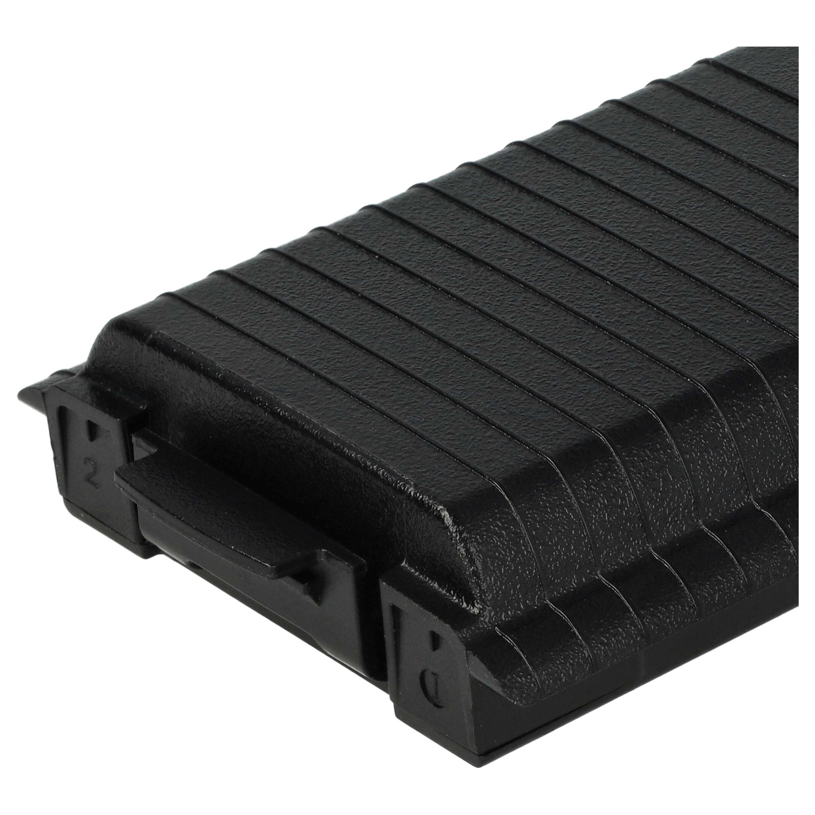 Eine schwarze rechteckige Plastikbox mit geriffelter Oberseite. Sie hat einen Griff und Markierungen. Der Hintergrund ist weiß.