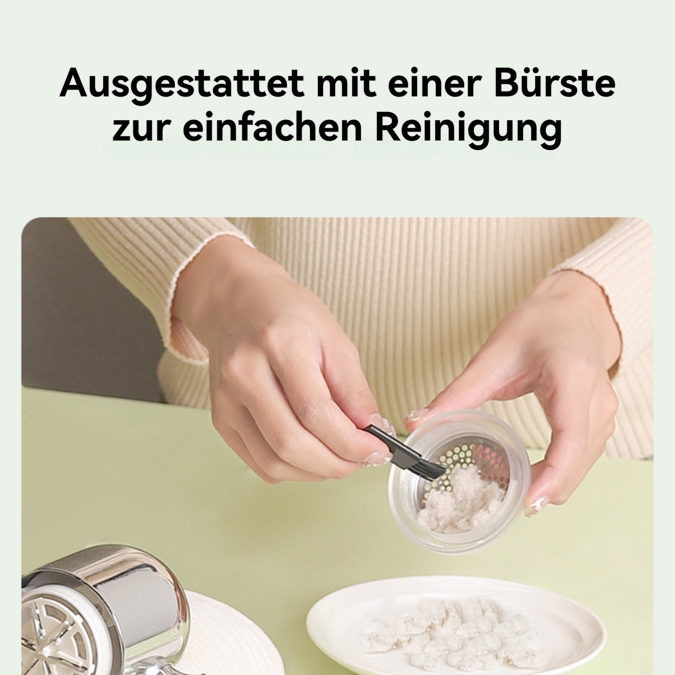 Eine Person reinigt einen kleinen Behälter mit einer Bürste. Staub liegt auf einem Teller. Der Hintergrund ist hellgrün.
