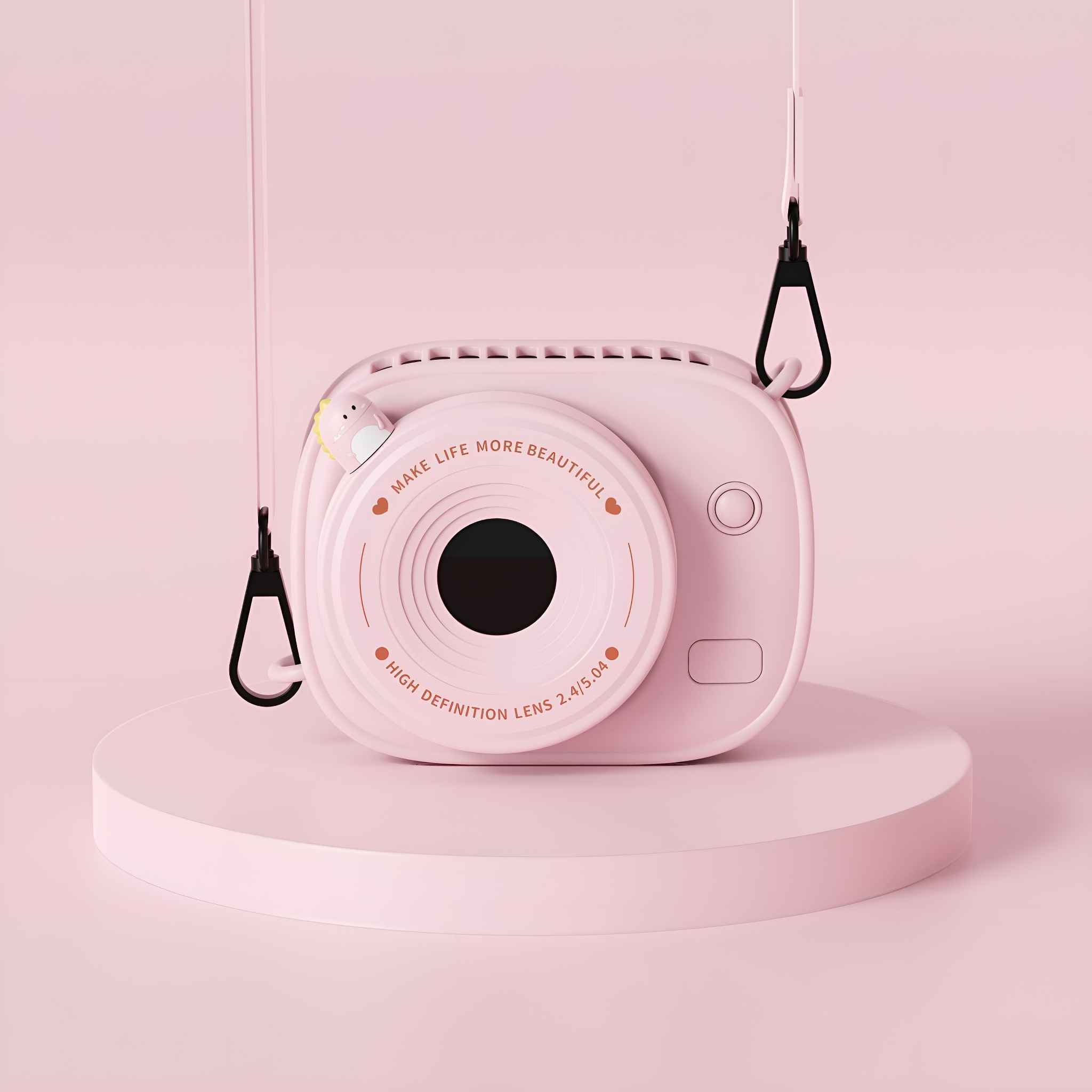 Rosa kameraförmiger Ventilator auf einer rosa Plattform. Er hat ein Objektiv, Knöpfe und einen Riemen. Der Hintergrund ist ebenfalls rosa.