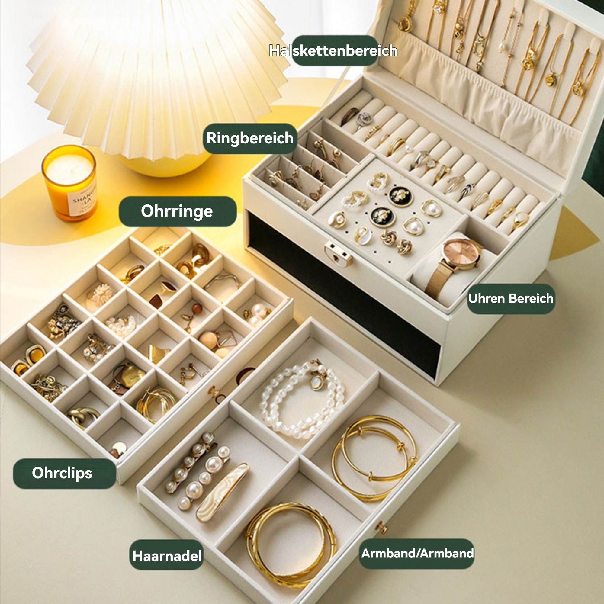Eine Schmuckschatulle mit Fächern. Enthält Ringe, Halsketten, Ohrringe, Armbänder und eine Uhr. Kerze und Lampe daneben.