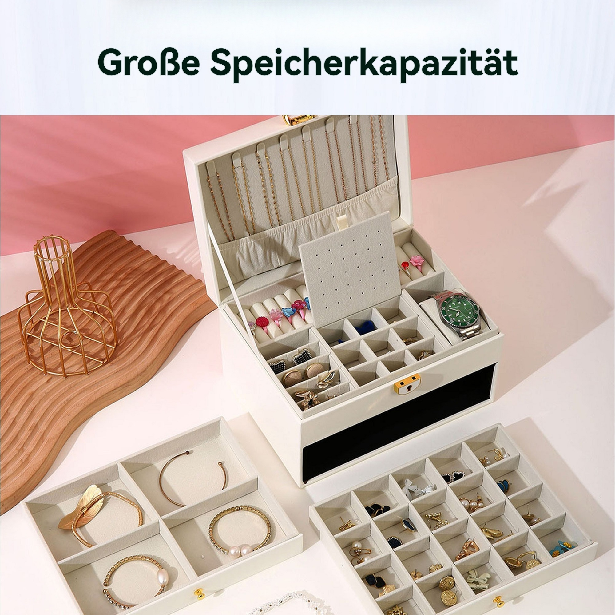 Eine offene, weiße Schmuckschatulle mit Schmuck. Tabletts mit Armbändern und Ohrringen stehen daneben. Eine Uhr ist in der Box.