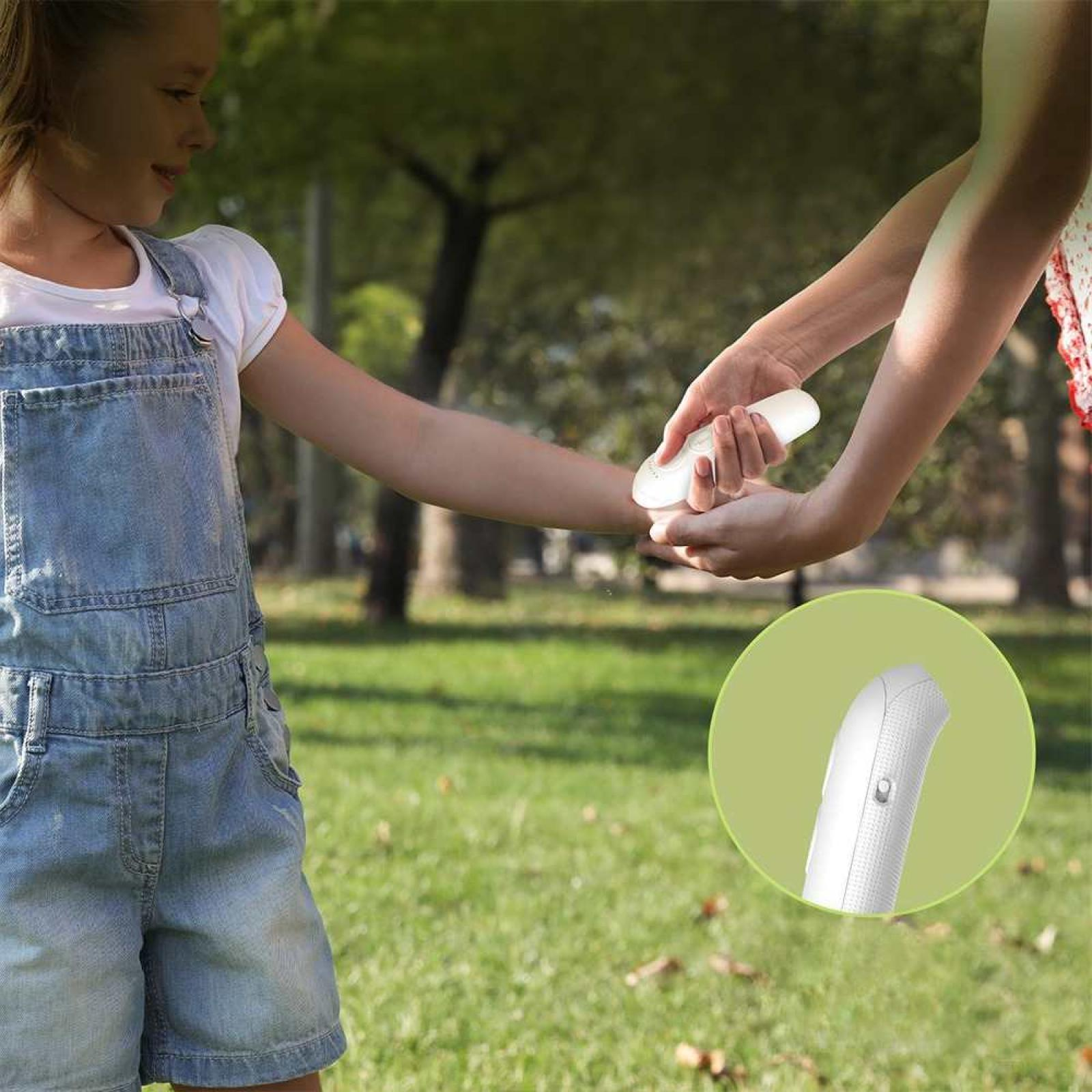 Ein Kind in Jeanslatzhose erhält ein weißes Gerät von einer Person. Der Hintergrund zeigt einen grünen Park mit Bäumen. Eine Einlage zeigt das Gerät.