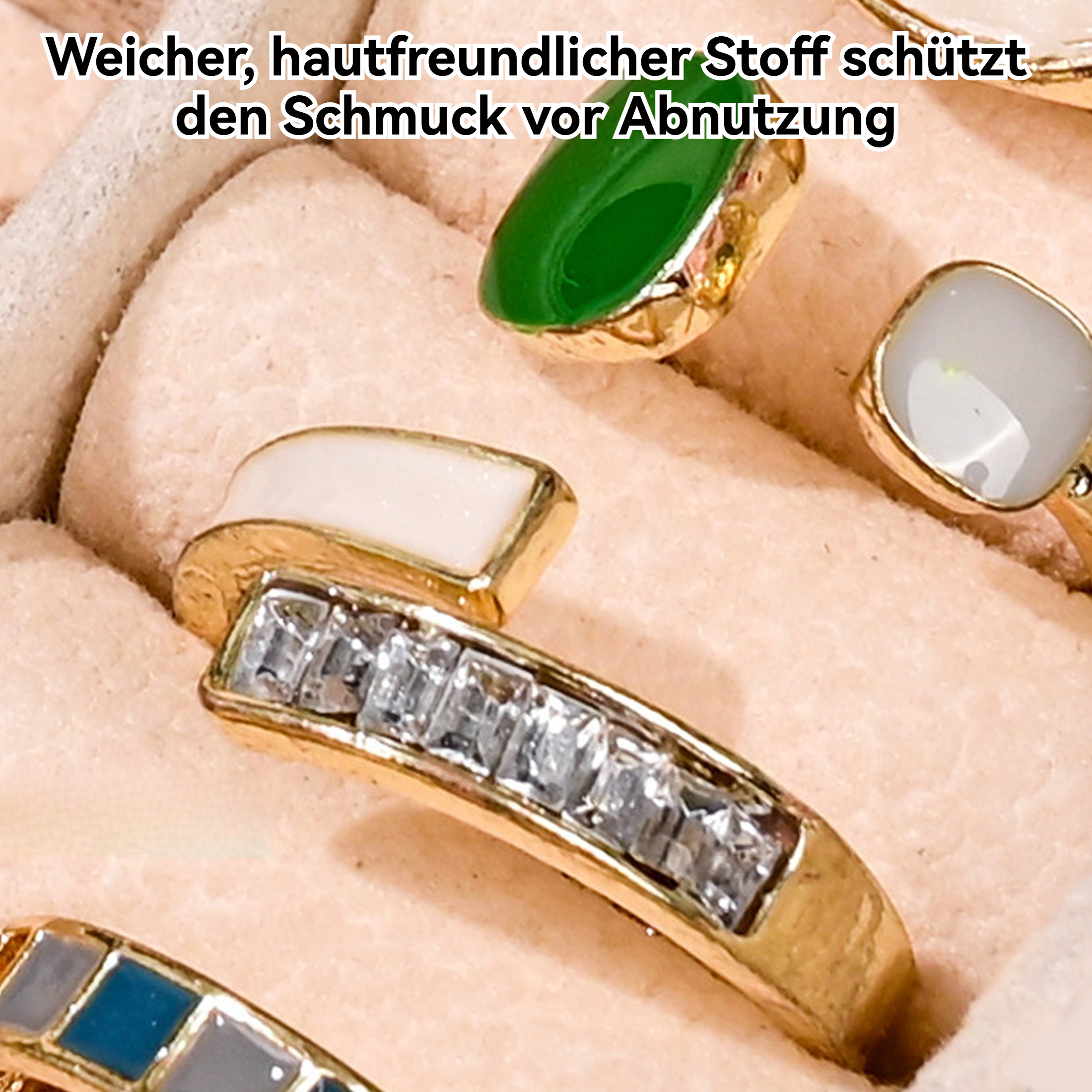 Nahaufnahme von Ringen mit Goldbändern und verschiedenen Edelsteinen in einer weichen, rosa Schmuckschatulle.