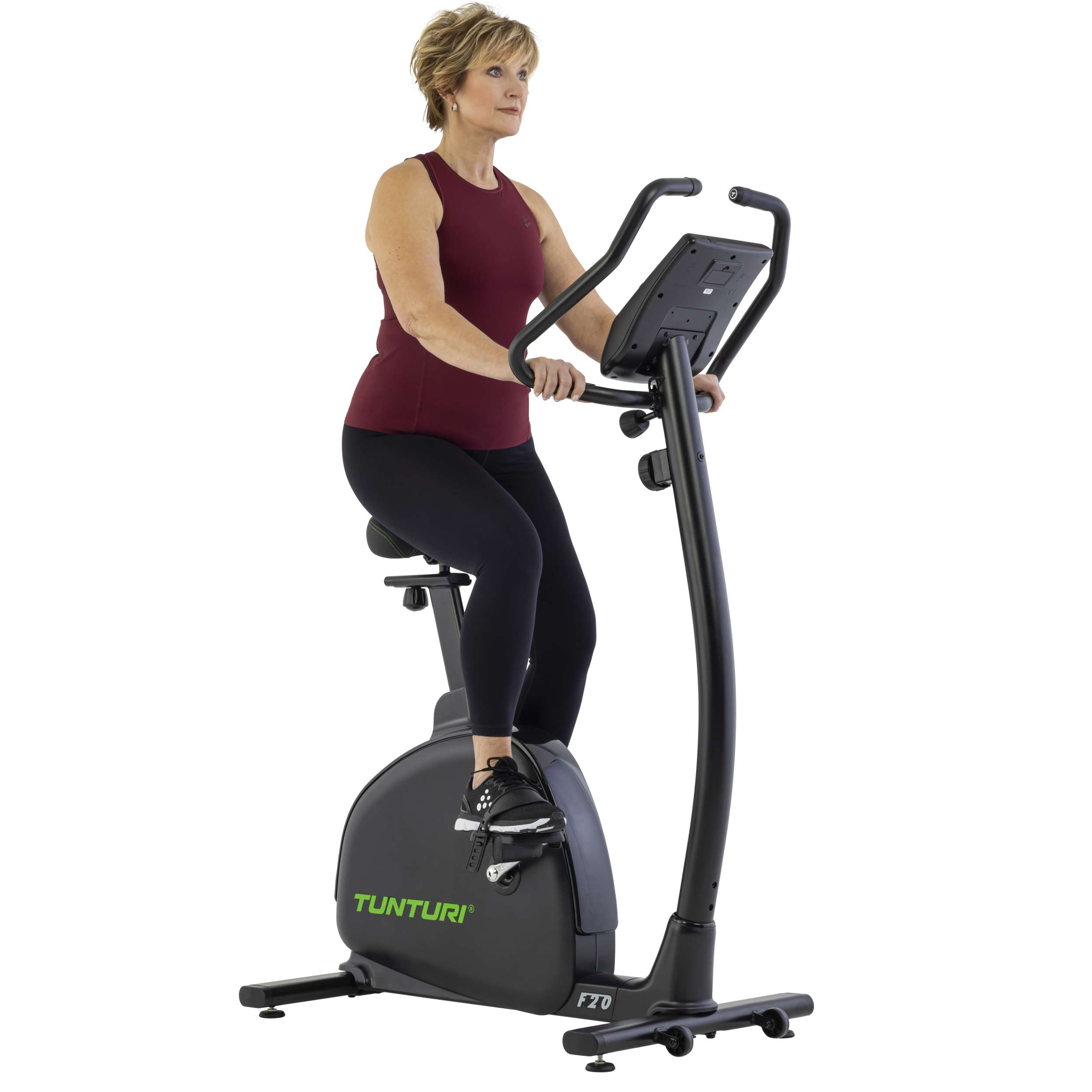 Een vrouw in een rode top en zwarte legging fietst op een hometrainer. De fiets is zwart, met het merk Tunturi.