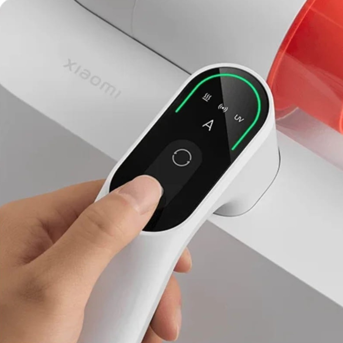 A hand presses a button on a white vacuum cleaner's control panel. The panel has a green-lit border and various icons.