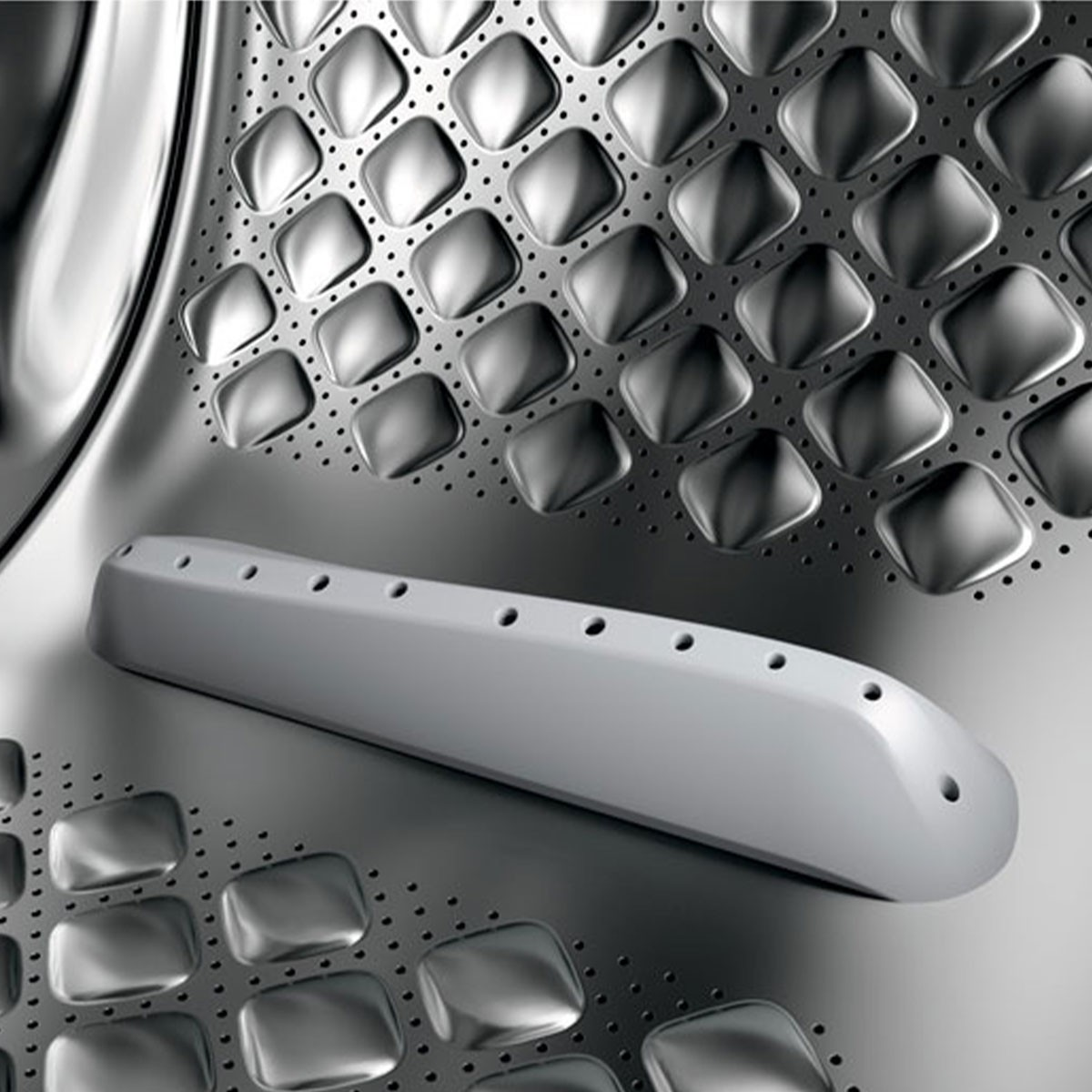 Primer plano del interior del tambor de una lavadora. Presenta una superficie metálica perforada con formas de diamante en relieve y un asa de plástico gris.