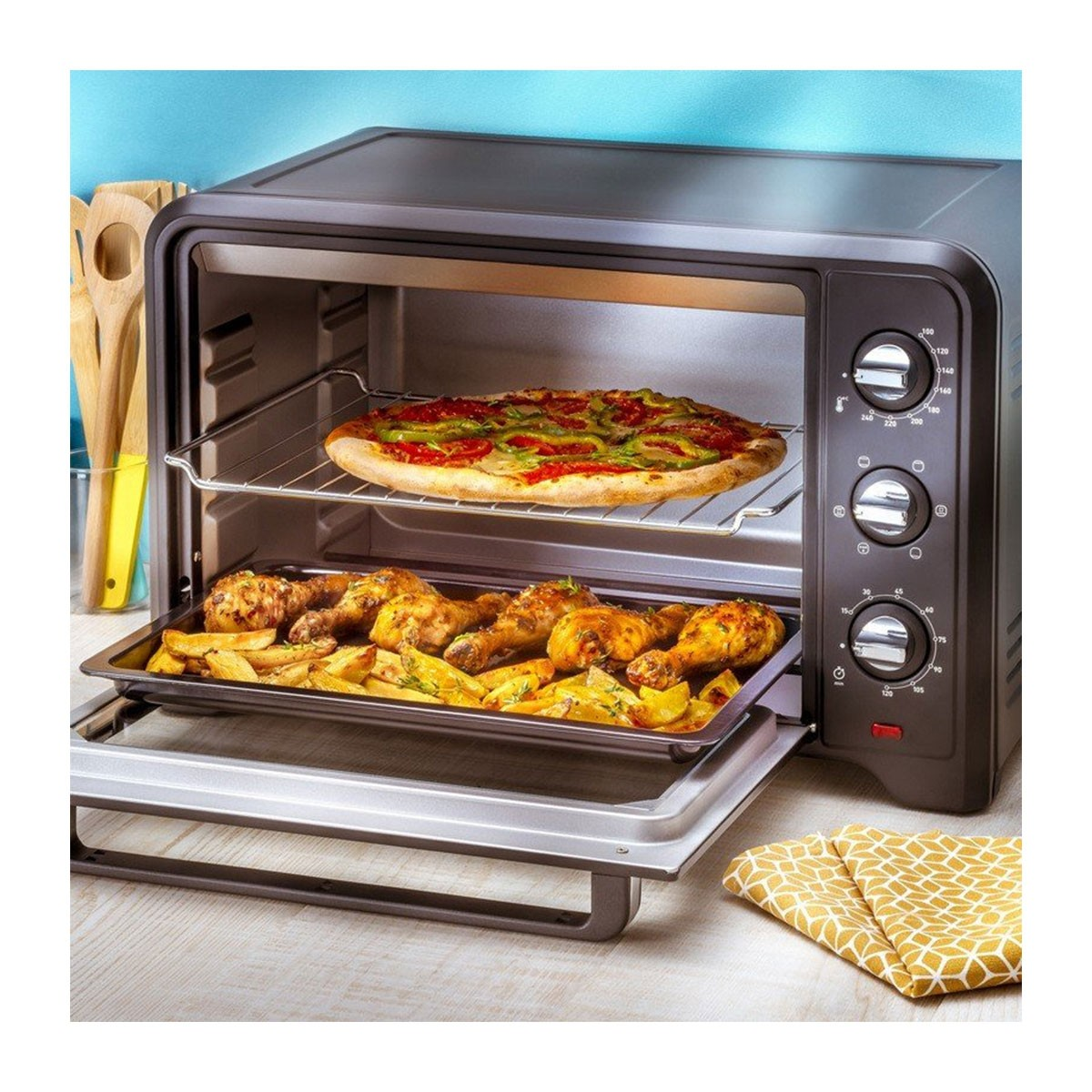 Un forno con pizza e pollo fritto all'interno. Il forno è nero. Un panno giallo a fantasia è a destra.