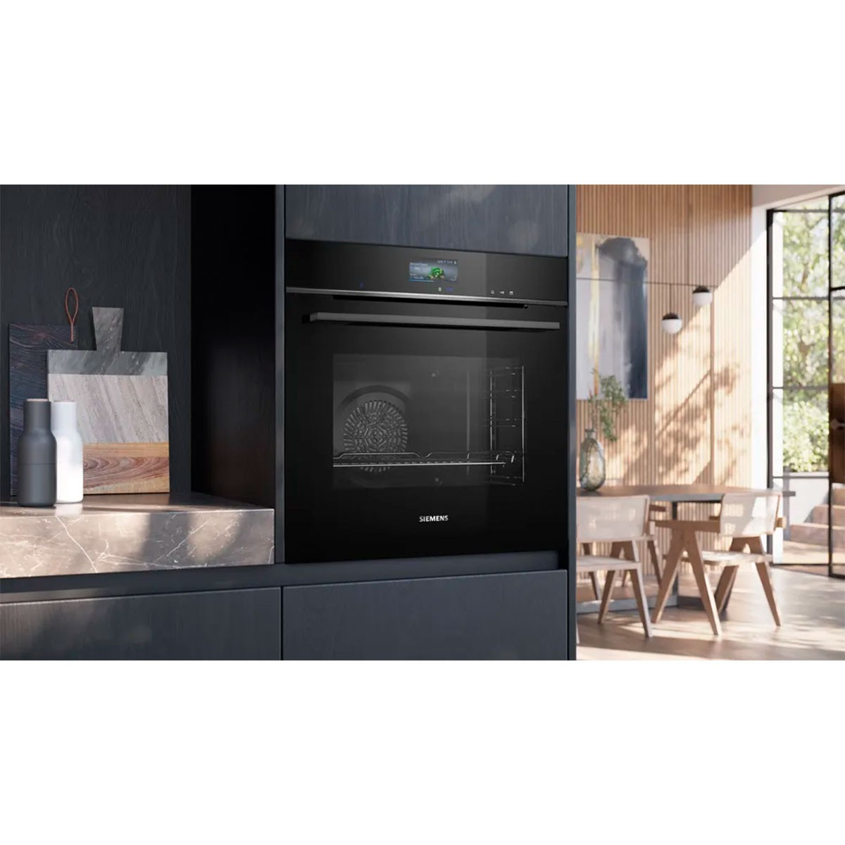 Een zwarte Siemens oven ingebouwd in een donkere keukenkast. Een marmeren aanrechtblad en een eethoek met daglicht zijn zichtbaar.