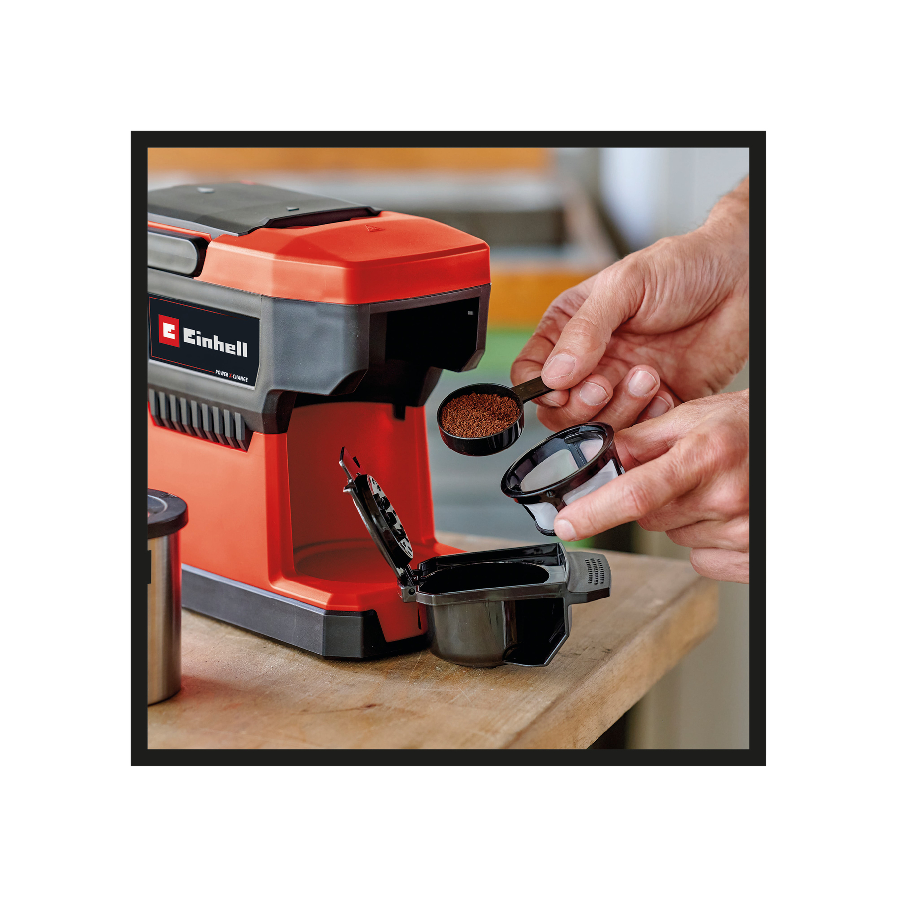 Osoba dodaje zmieloną kawę do ekspresu do kawy. Maszyna jest czerwona i czarna. Trzymana jest miarka i filtr.