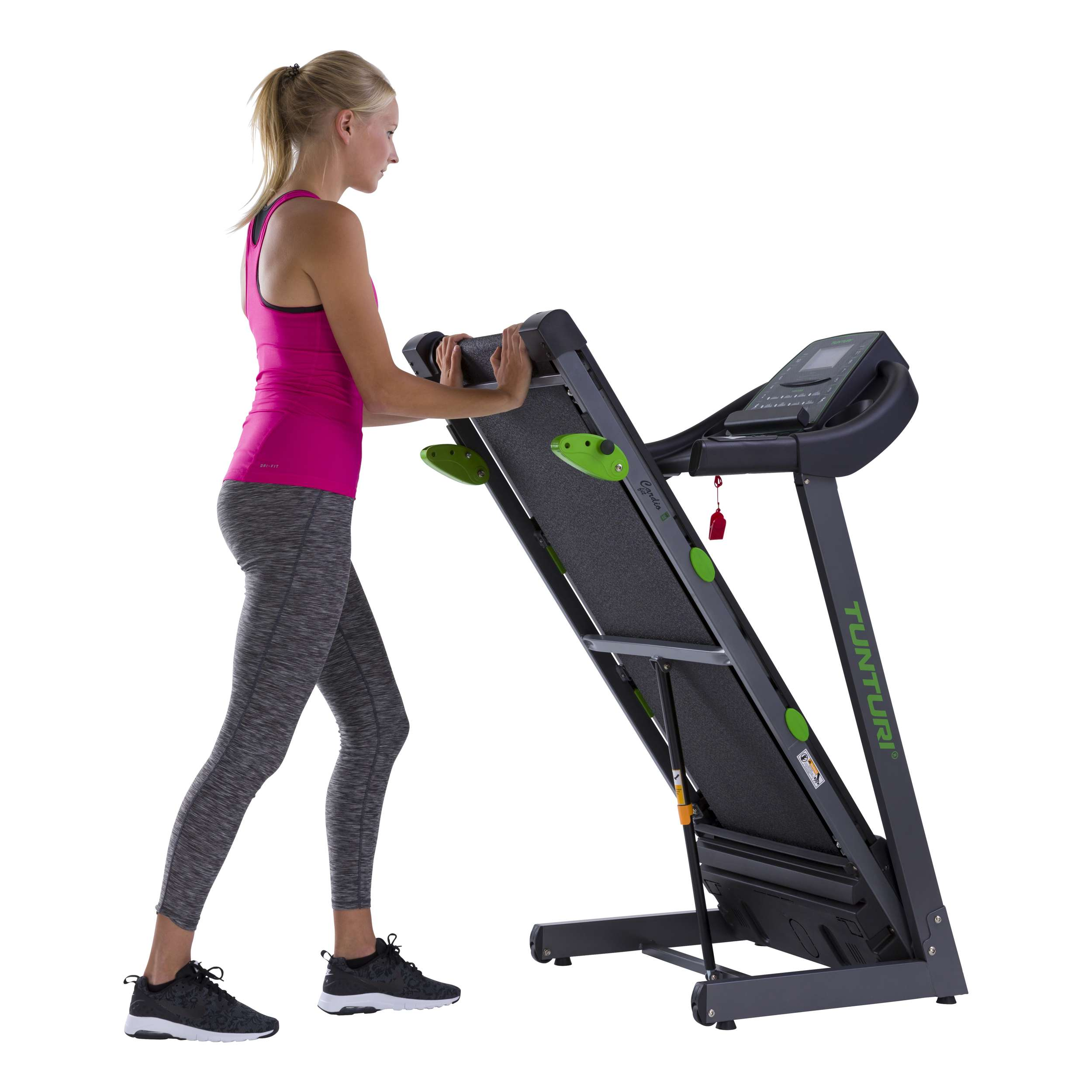 Een vrouw in sportkleding leunt op een loopband. Hij is zwart en groen. De vrouw heeft blond haar en is aan het sporten.