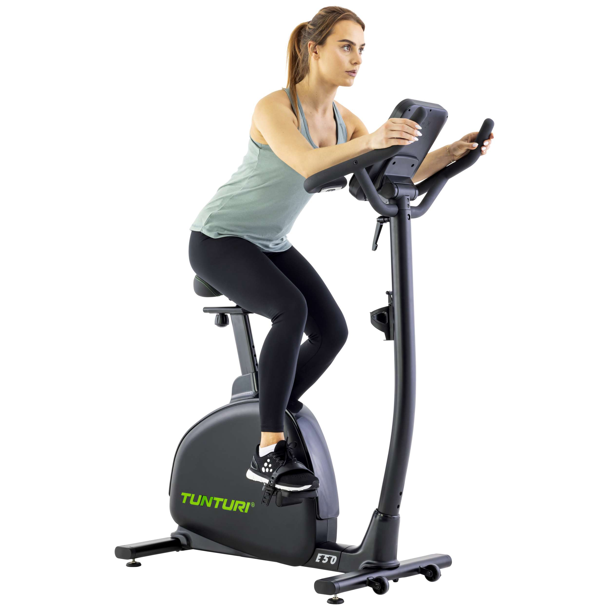Een vrouw op een hometrainer. Ze draagt een groene top en zwarte leggings. De fiets is zwart met groene details.