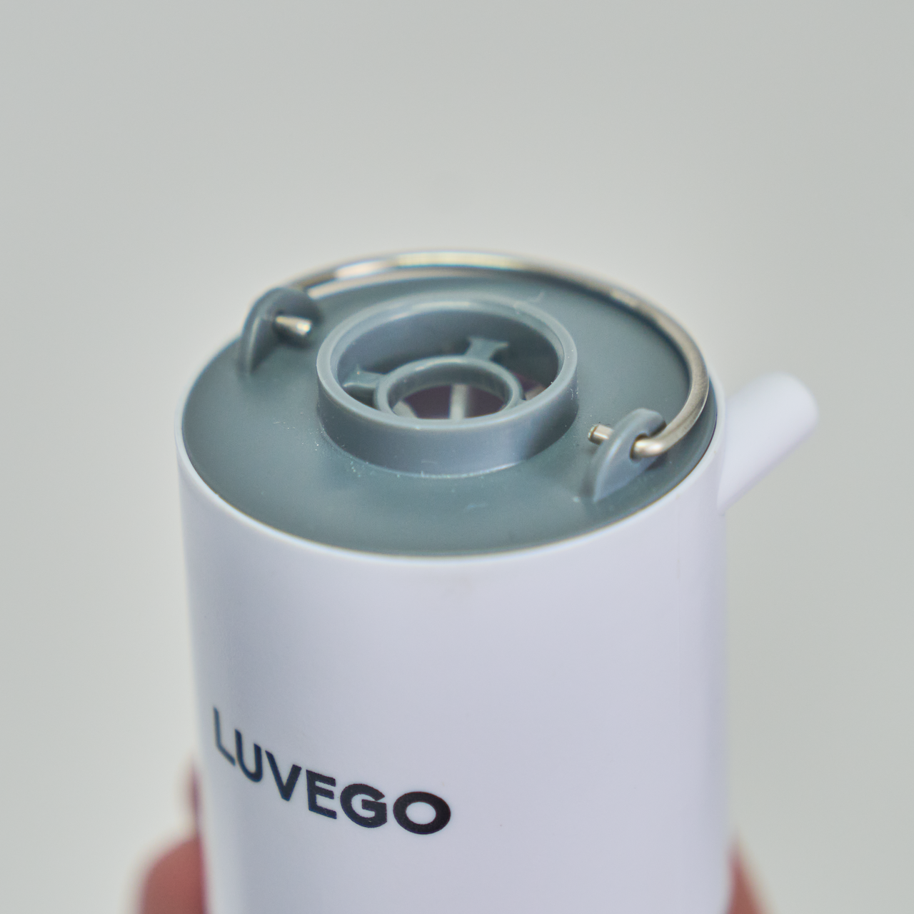 Nahaufnahme eines weißen Wasserspenders mit grauem Deckel. Das Wort "LUVEGO" ist auf der Seite aufgedruckt. Der Hintergrund ist hellgrau.