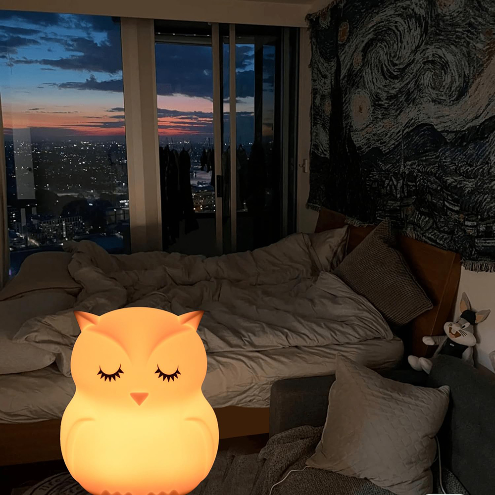 Eulenlampe auf Bett. Sonnenuntergang durch Fenster. Bett mit Kissen und einem Sternennacht-Wandteppich. Hasenplüschtier.
