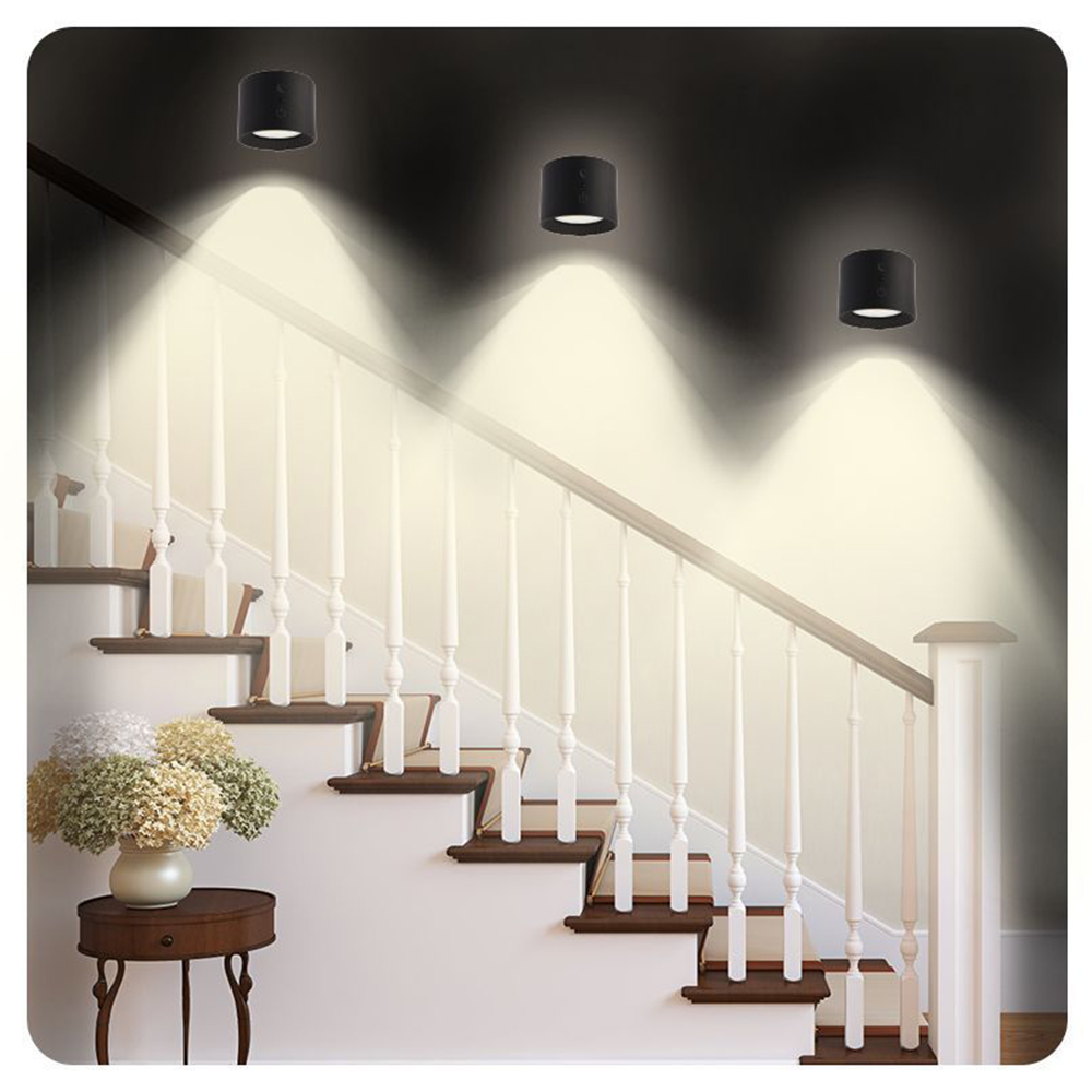 Treppe mit drei Deckenleuchten. Die Lichter scheinen auf die Treppe. Eine Vase mit Blumen steht auf einem kleinen Tisch.
