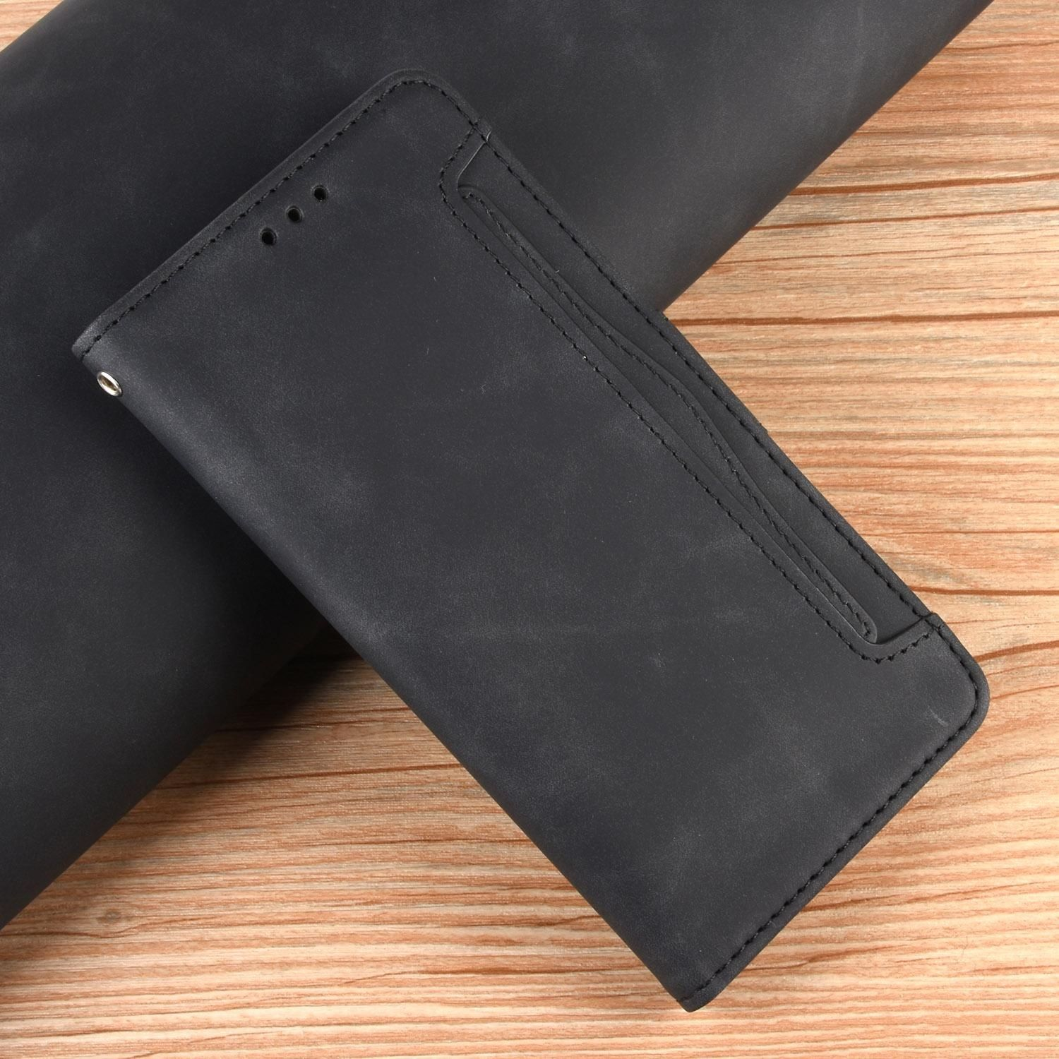 Eine schwarze Leder-Handyhülle liegt auf einer dunklen Oberfläche. Die Hülle ist offen und gibt einen helleren Holztextur-Hintergrund frei.
