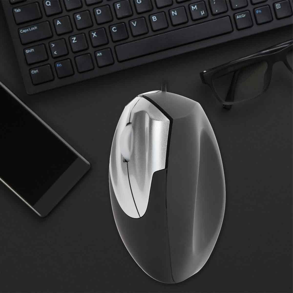 Eine schwarze Computermaus, Tastatur, Brille und ein Smartphone befinden sich auf einer schwarzen Oberfläche. Die Maus ist im Fokus.