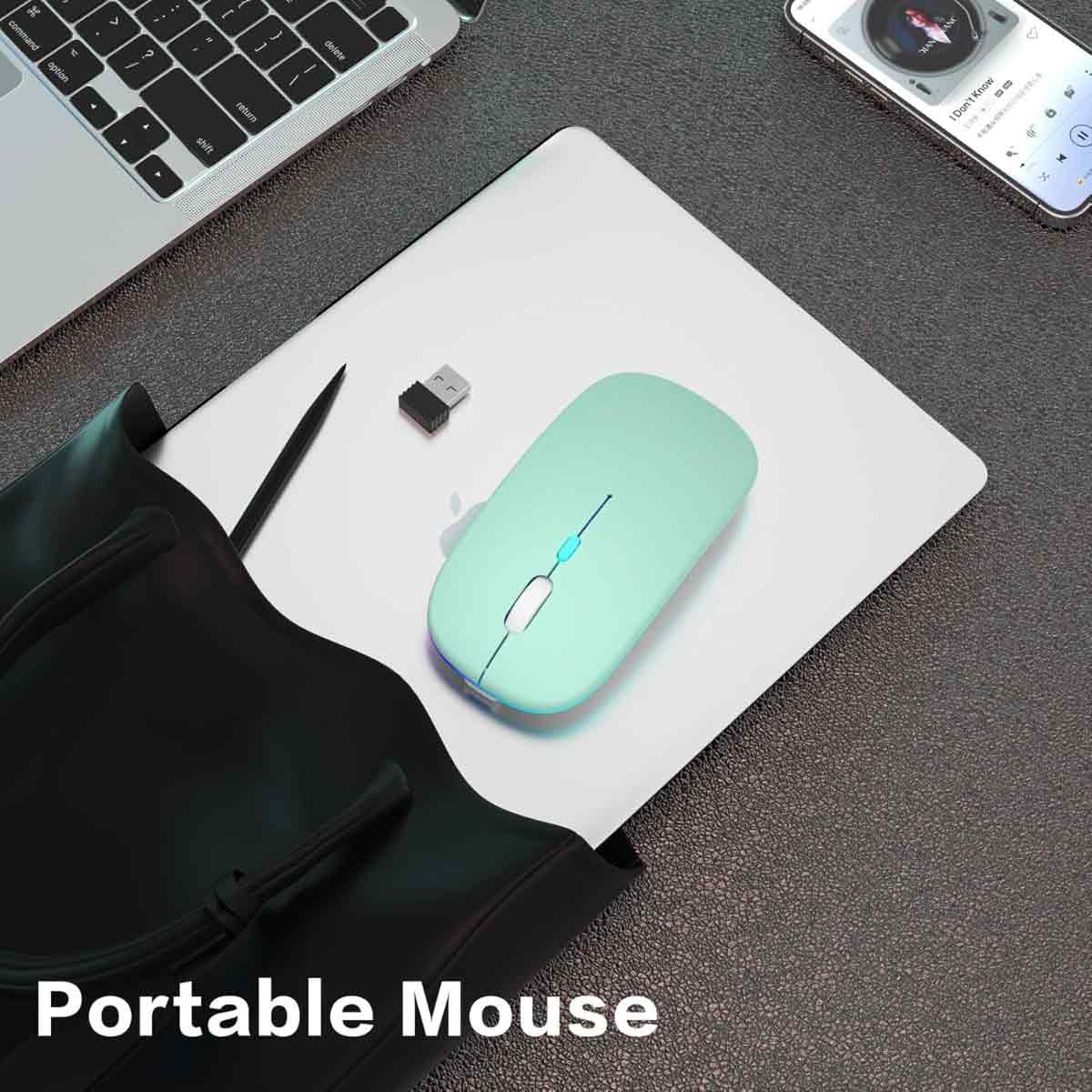 Eine hellgrüne drahtlose Maus, ein USB-Empfänger, ein Laptop und ein Smartphone liegen auf einer weißen Oberfläche. Schwarze Tasche links.