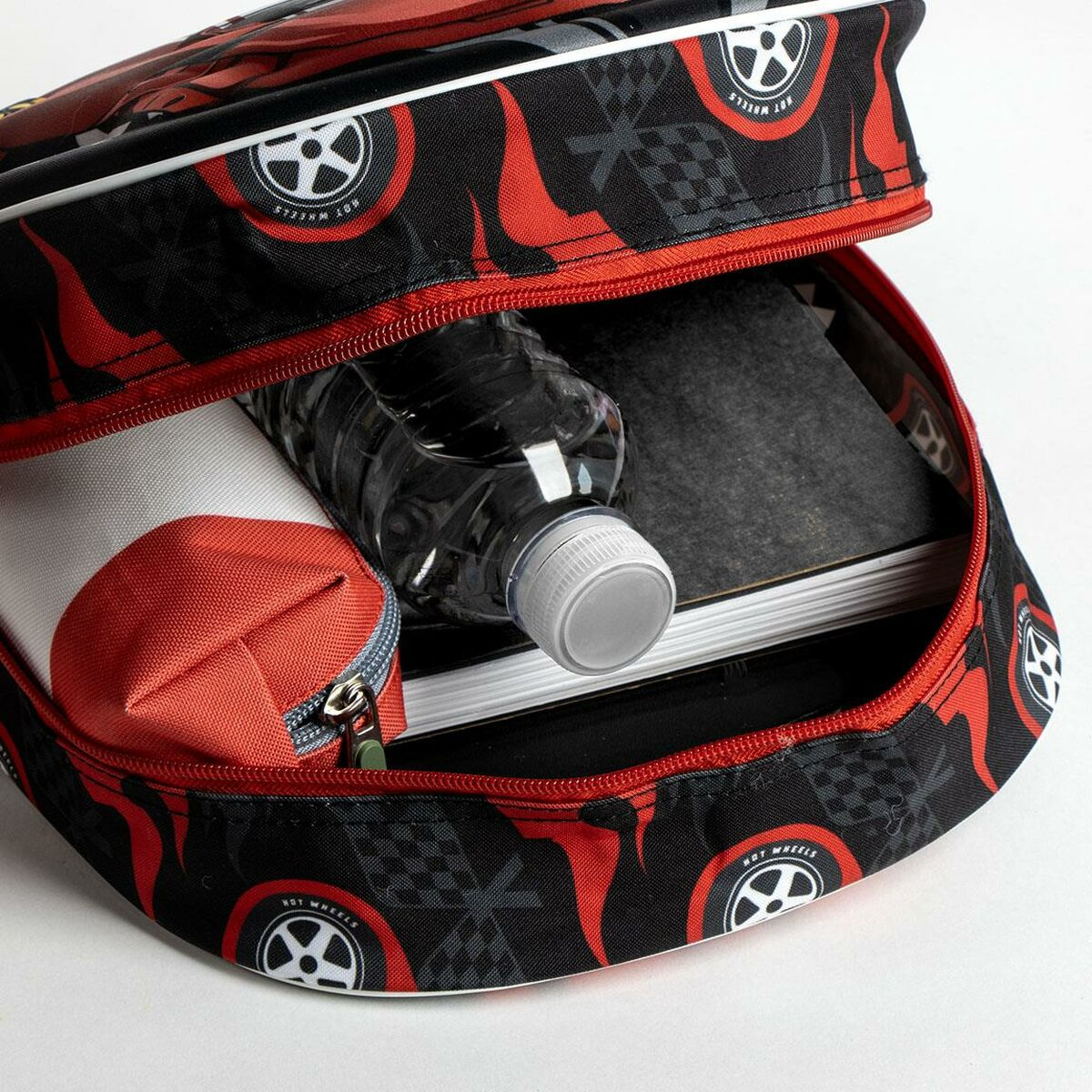 Offener Rucksack mit Wasserflasche, Notizbuch und Federmäppchen. Der Rucksack ist schwarz mit roten Akzenten und Hot Wheels Logos.