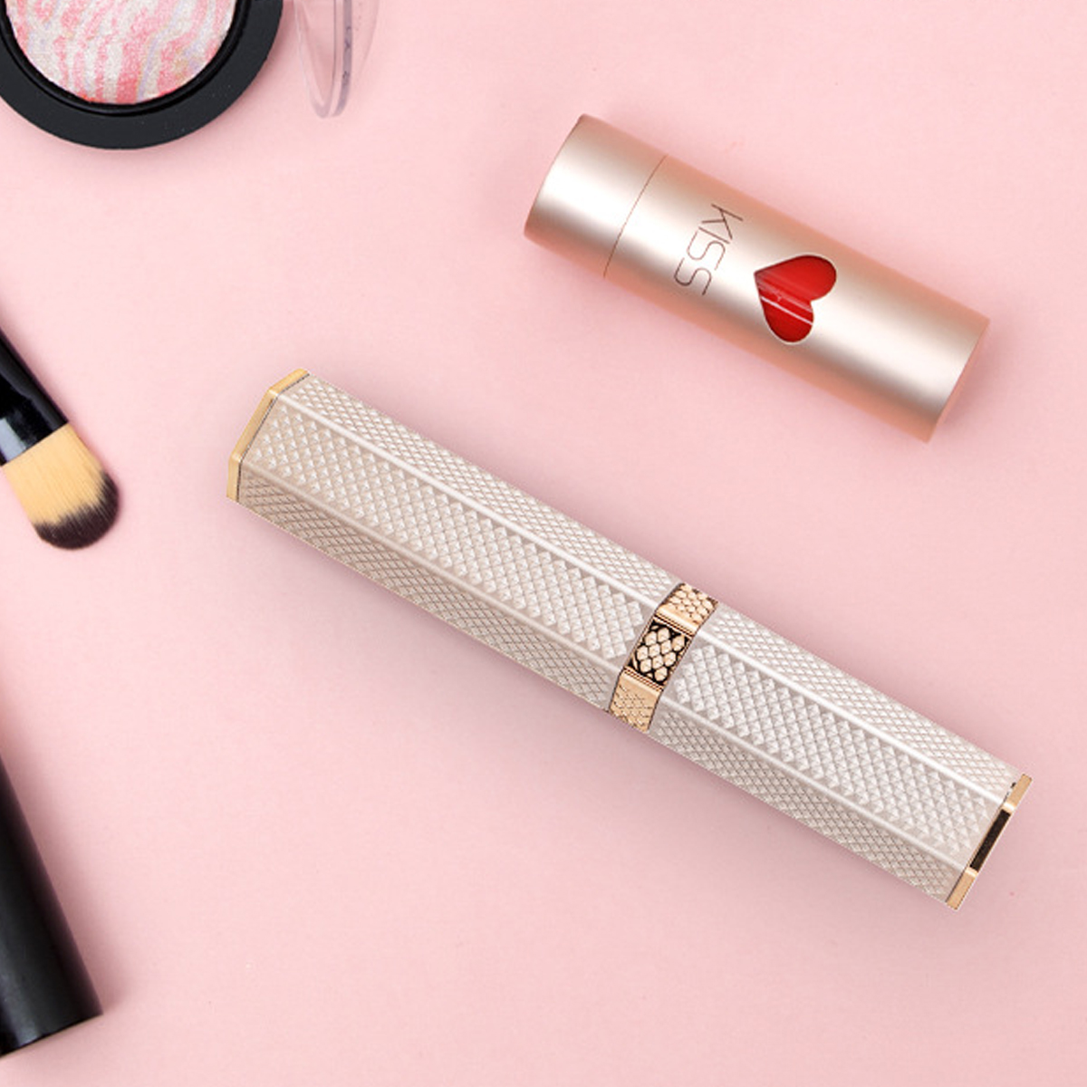 Kosmetika auf rosa Hintergrund. Lippenstift, Make-up-Pinsel, Kompaktpuder und eine dekorative Parfümflasche sind zu sehen.