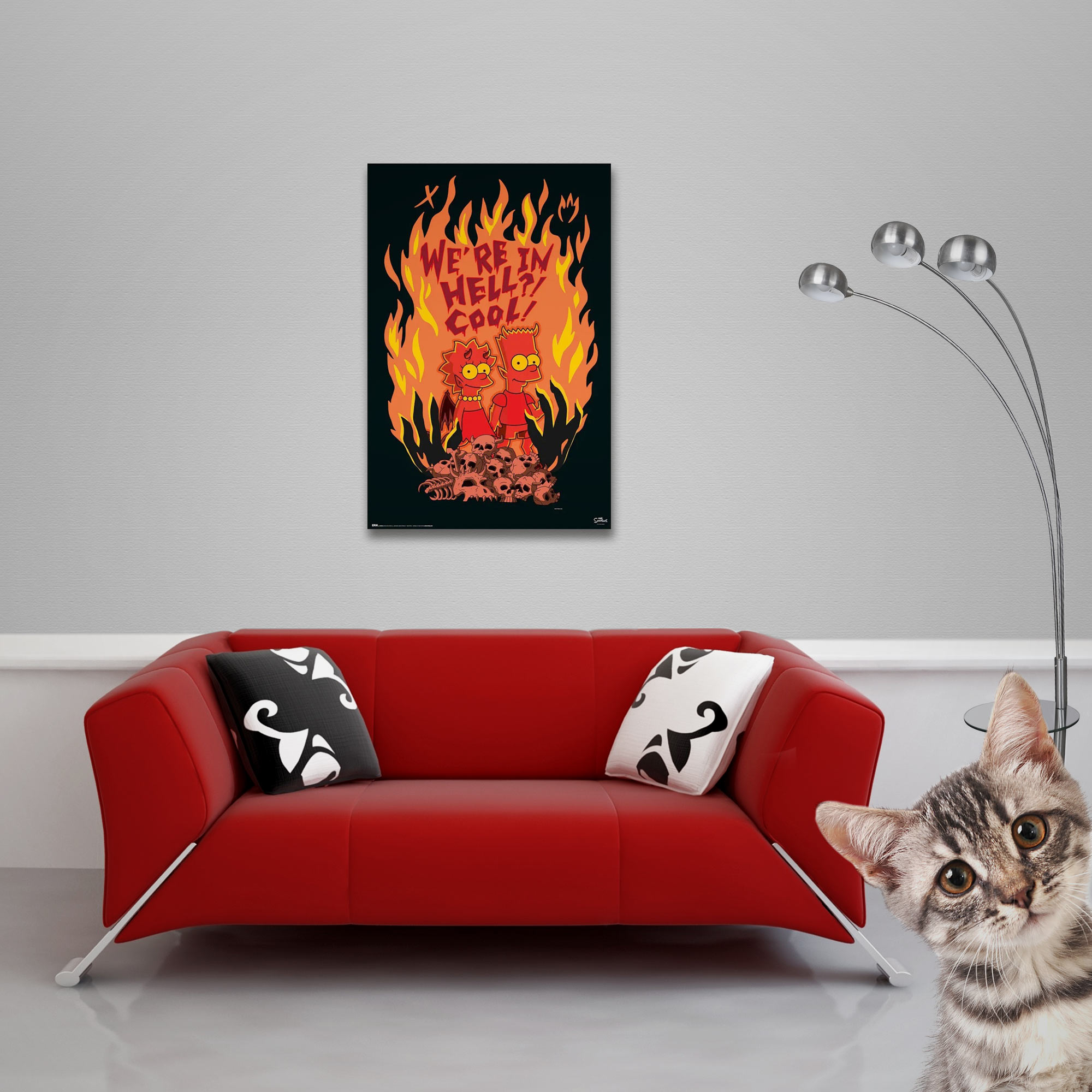 Ein rotes Sofa mit Kissen, ein Poster von Simpsons in der Hölle, eine Lampe und eine Katze.