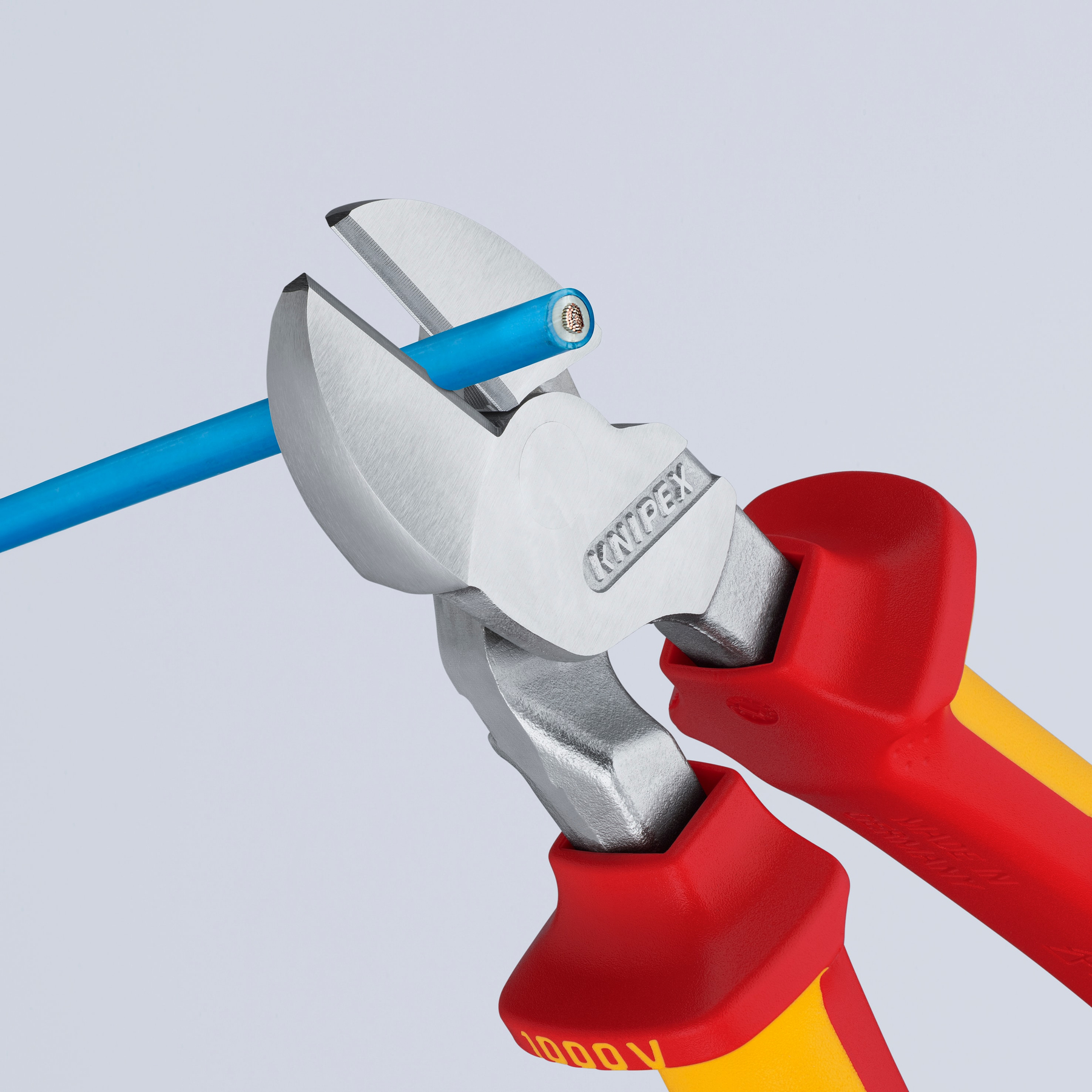 Zange schneidet blaues Kabel. Rote und gelbe Griffe, silberne Schneidklingen. Weißer Hintergrund. Die Zange hat das KNIPEX-Logo.