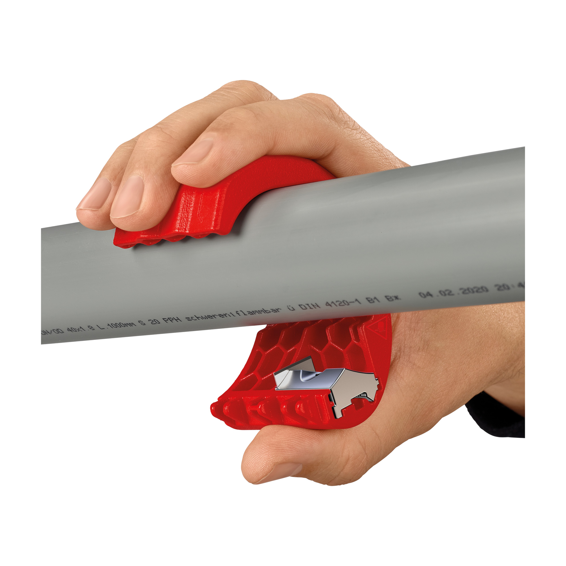 A hand holds a red pipe cutter around a gray pipe. The cutter has a blade. The background is white.