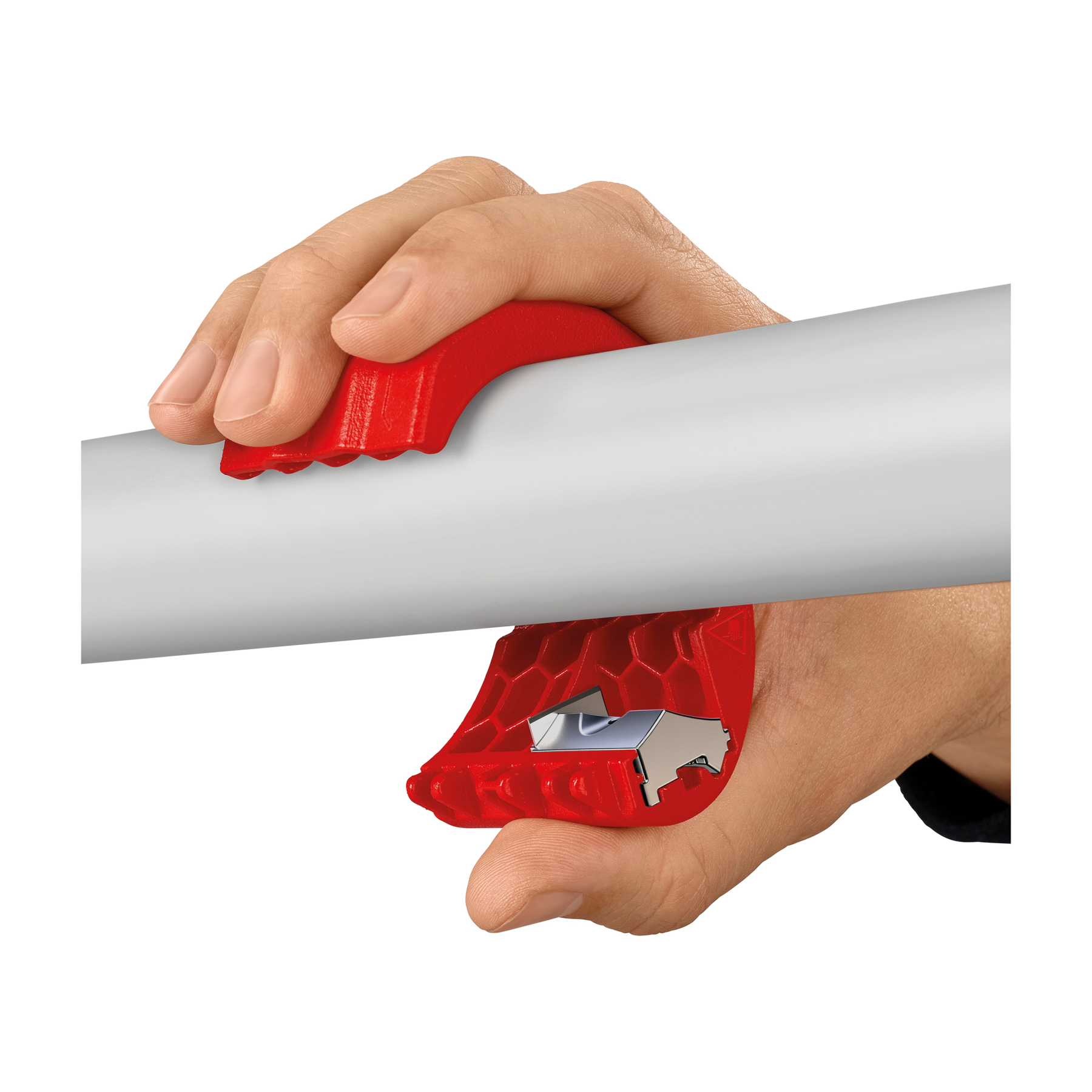 A hand holds a red pipe cutter around a white pipe. The tool has a blade. The background is white.