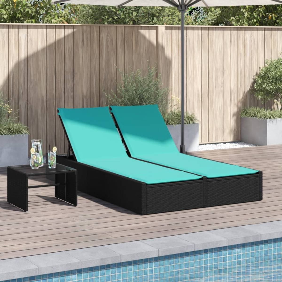 Zwei schwarze Korbliegen mit türkisfarbenen Kissen neben einem kleinen Tisch mit Getränken auf einem Holzdeck am Pool.