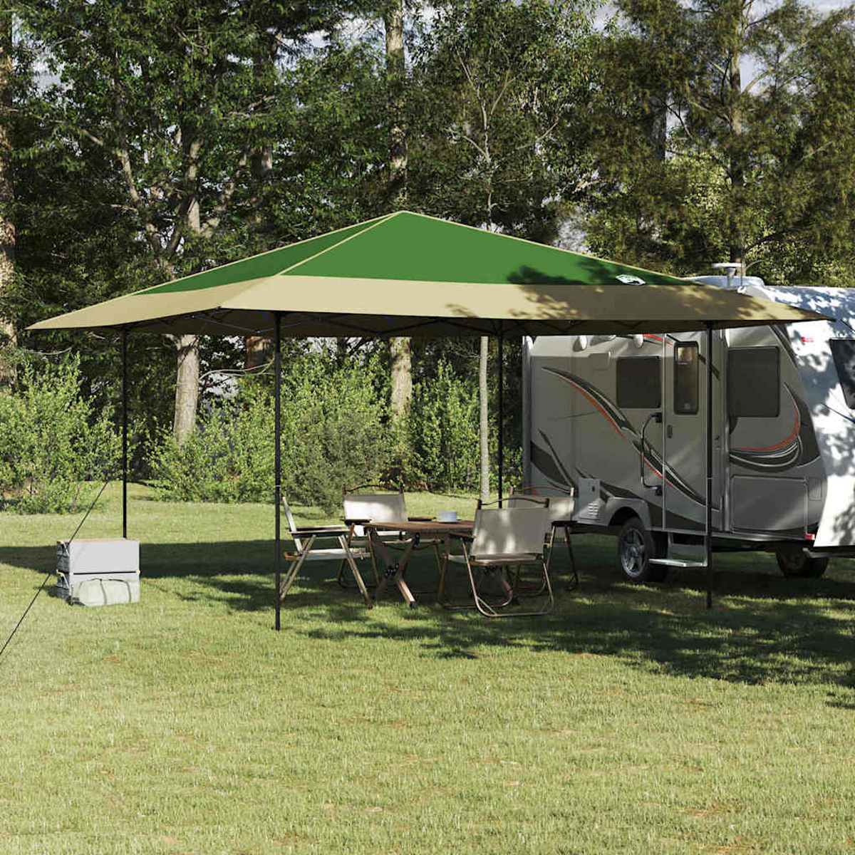 Ein grünes und beiges Vordach über einem Tisch und Stühlen. Ein Wohnmobil parkt in der Nähe auf Gras, mit Bäumen im Hintergrund.