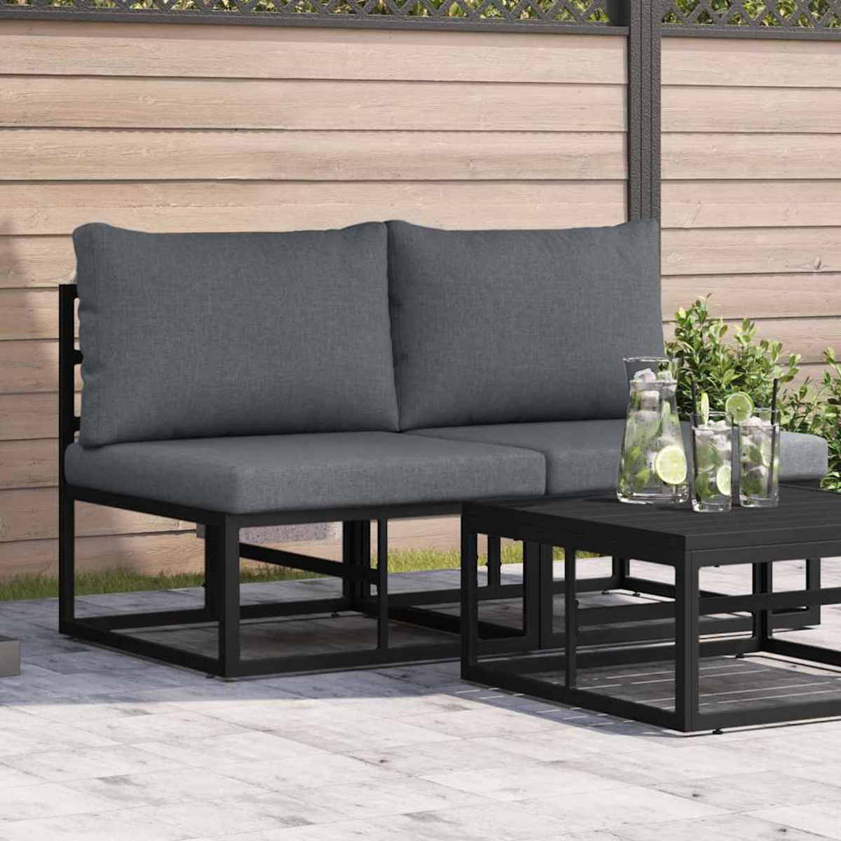 Asientos al aire libre con cojines grises y marco negro, junto a una mesa con bebidas. Fondo de madera.