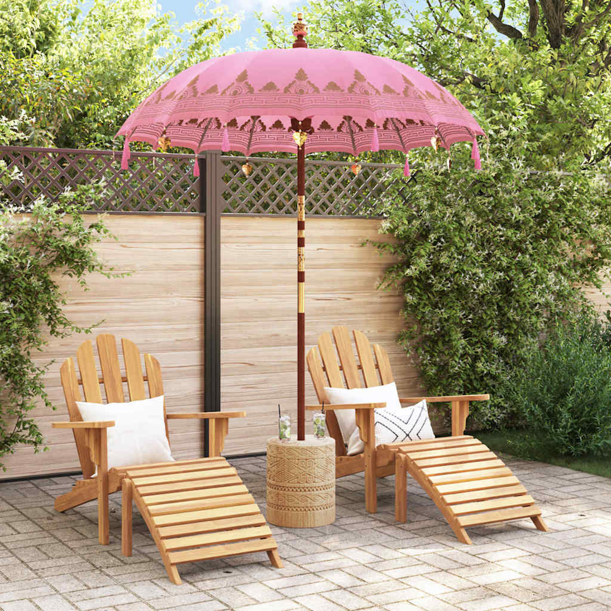 Eine Terrasse mit zwei Holzstühlen, einem rosa Schirm und einem kleinen Tisch. Grüne Pflanzen befinden sich im Hintergrund.