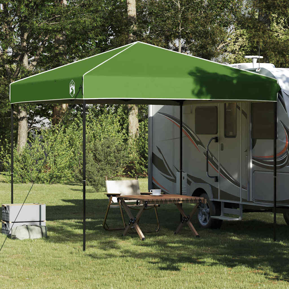 Tenda da sole verde sopra un tavolo e sedie vicino a un camper. Sfondo foresta. Tavolo con una tazza. Allestimento da campeggio.