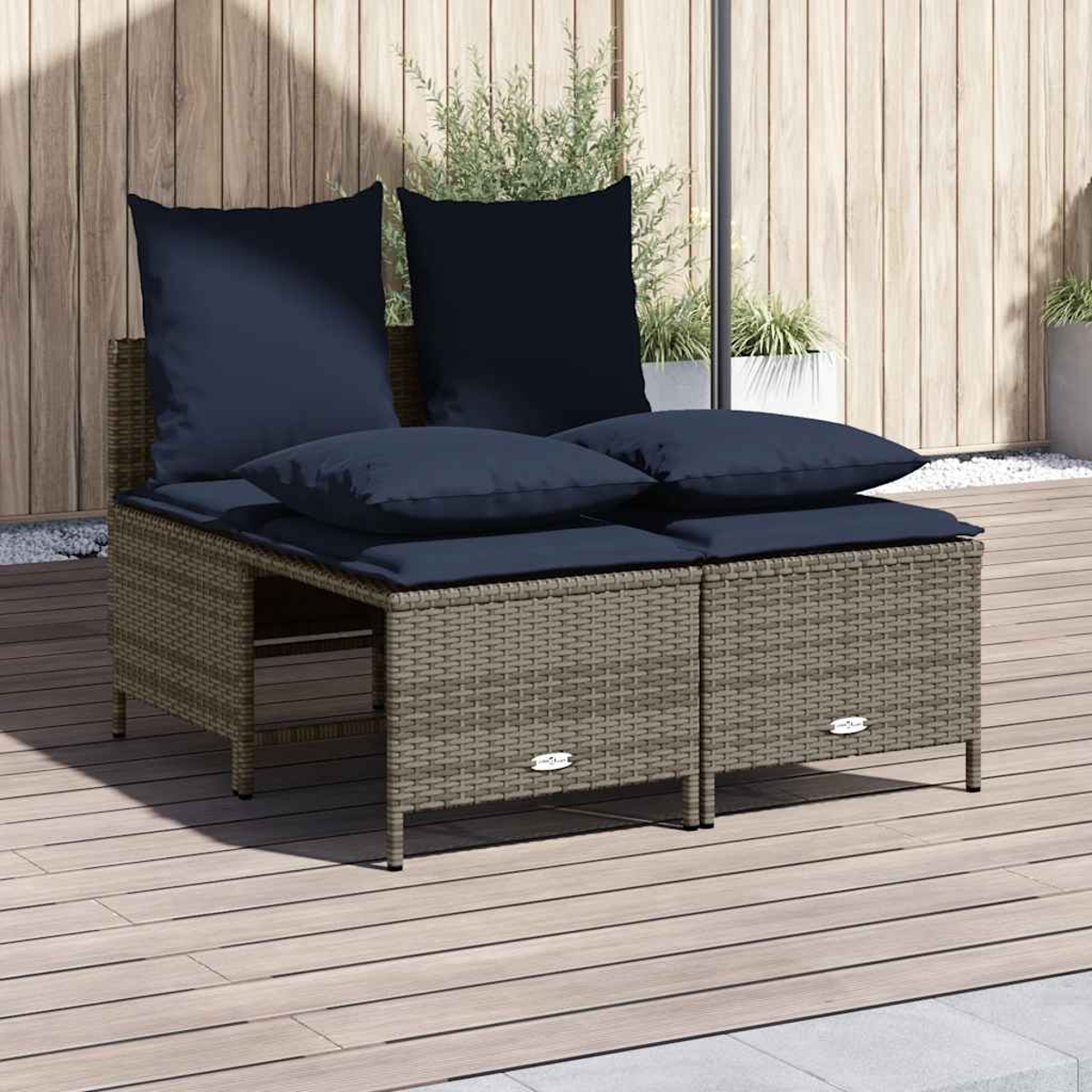 Outdoor-Korbsofa mit marineblauen Kissen auf einem Holzdeck, vor einer Holzwand. Pflanzen sind im Hintergrund sichtbar.