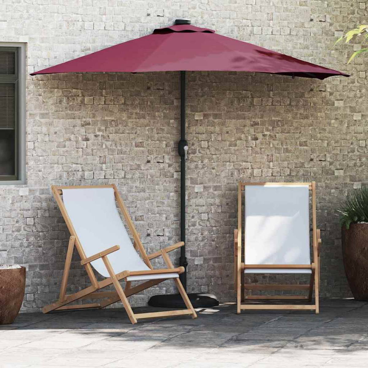 Due sedie in legno con seduta bianca e un ombrellone bordeaux su un patio. Un muro di mattoni fa da sfondo.