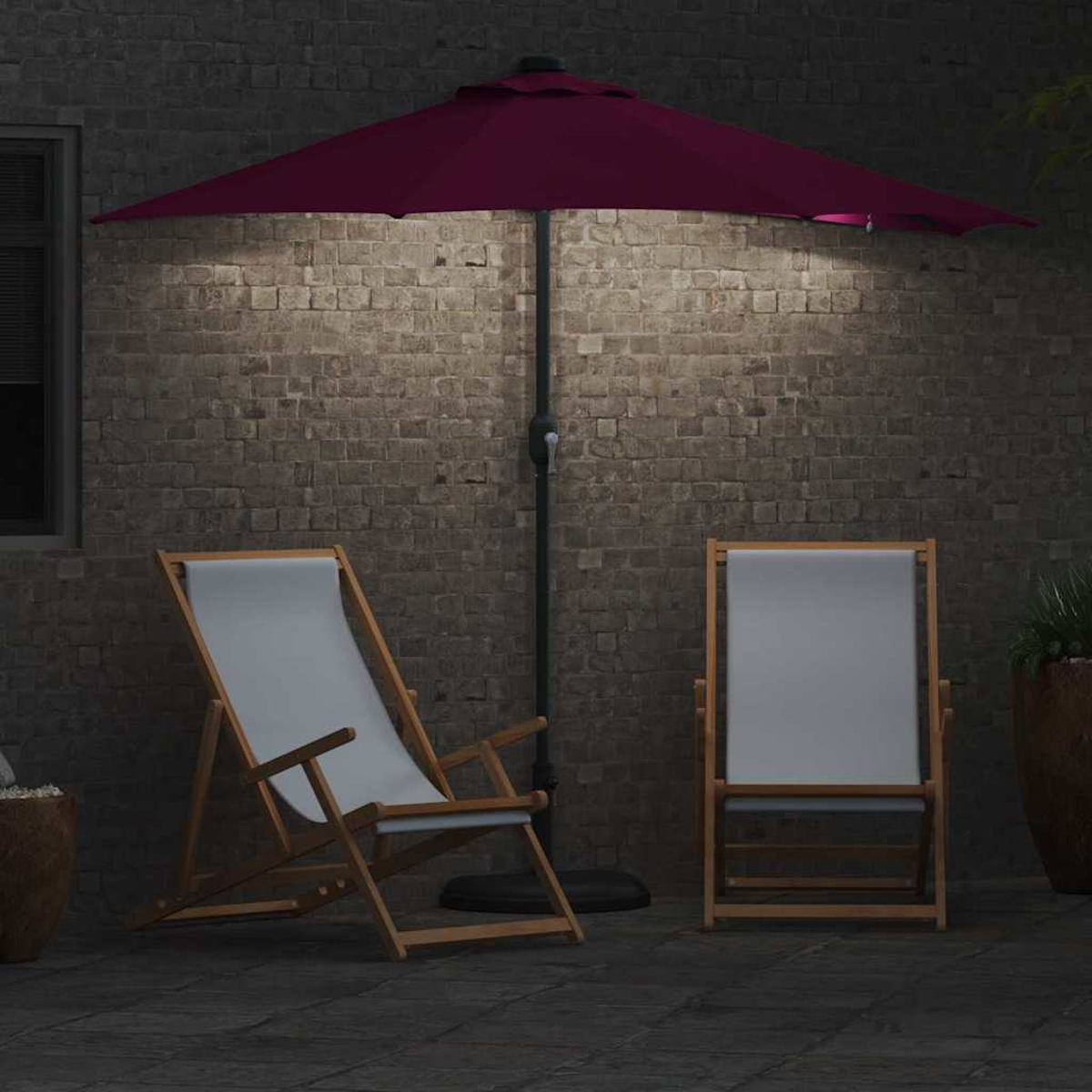 Due sedie, un ombrello e un muro di mattoni. La scena è illuminata da una calda luce.