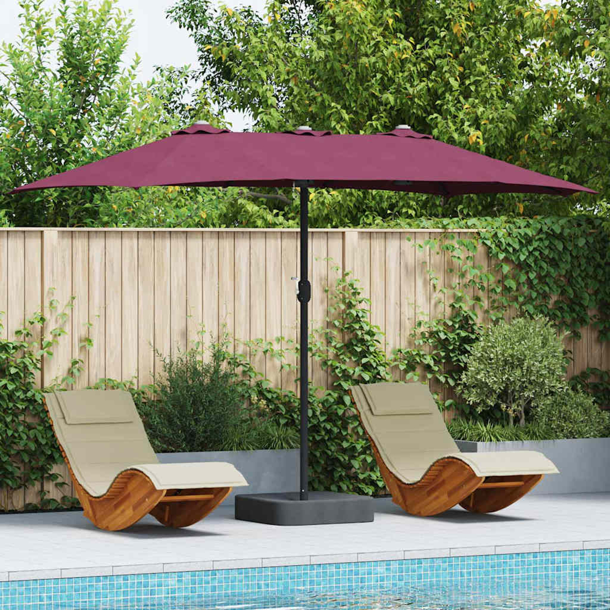 Una scena del patio con due sedie a dondolo in legno, un ombrello bordeaux, una piscina e una recinzione in legno circondata da piante.
